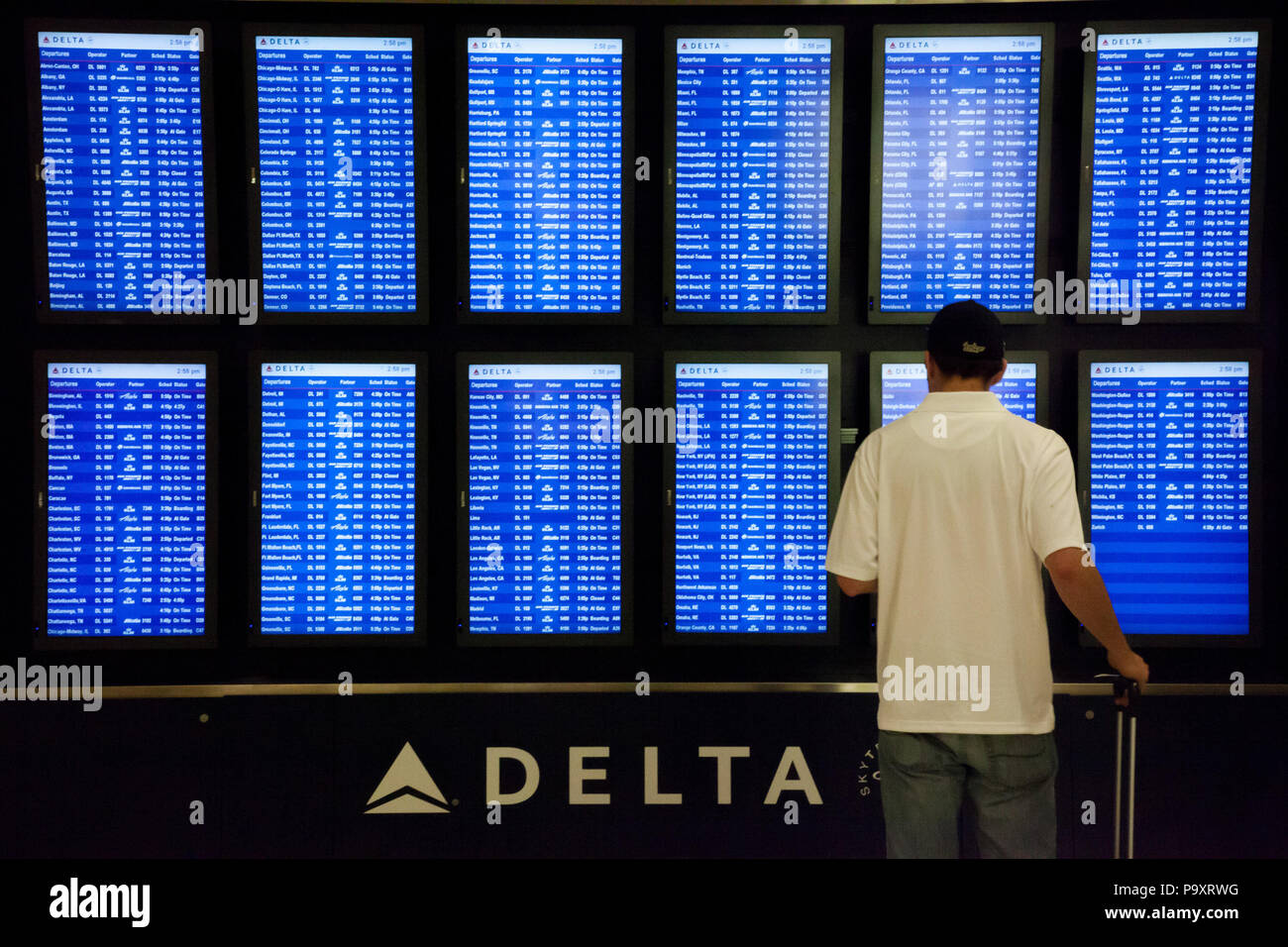 A passenger stands near the flight information panel depicting services of Delta Airlines and its partners at Atlanta International Airport, USA Stock Photo
