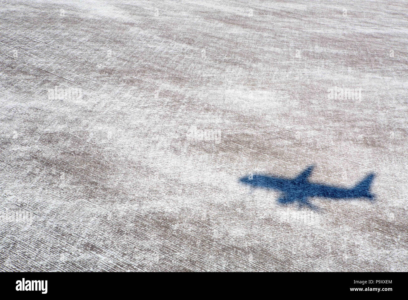 A civil aircraft drops a shadow on a snow-covered field under the jet's final approach path Stock Photo
