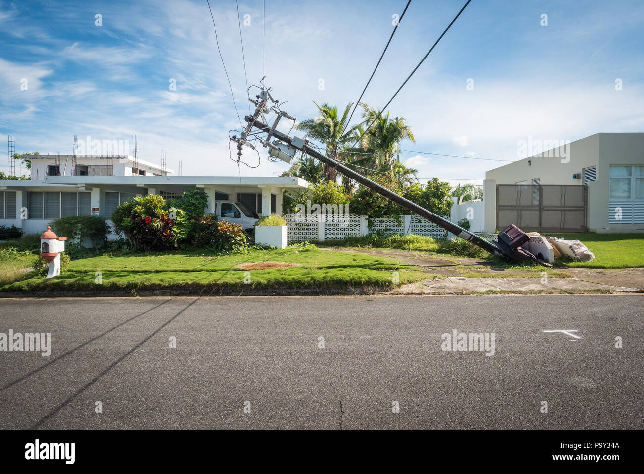 A telephone pole leans dangerously close to a house in Puerto Rico after Hurricane Maria destroyed much of the island's infrastructure in 2017. Stock Photo