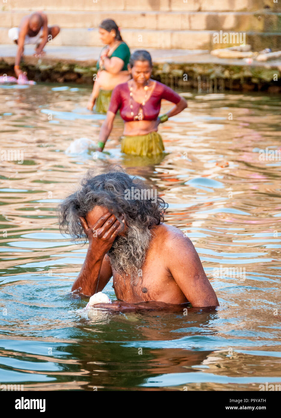 Indian sadhu man and 2 women bathing in the Ganges at dawn  Varanassi Indian Stock Photo
