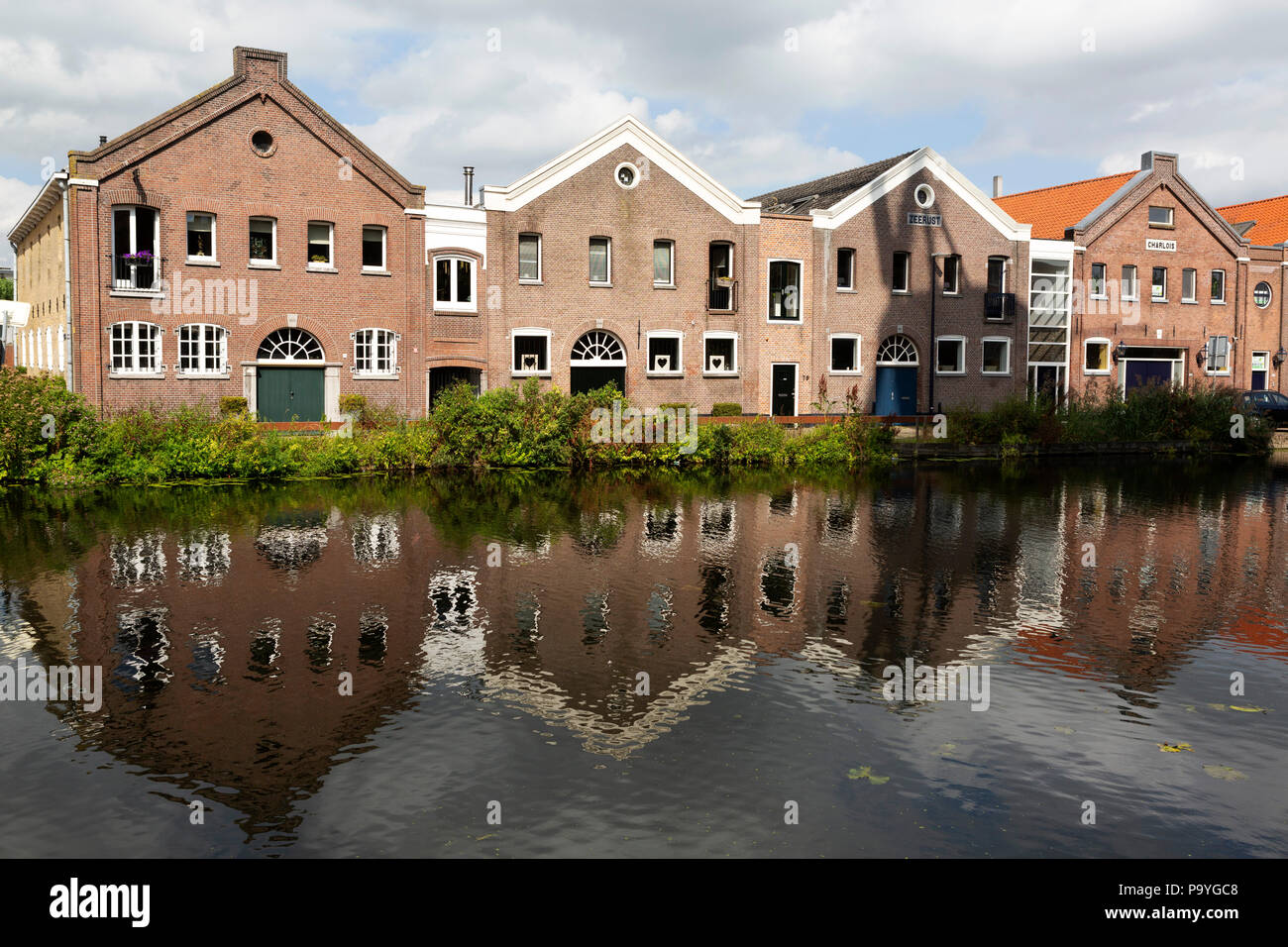 Building facades reflect in the water of the Nordvestsingel at Schiedam, the Netherlands. The canal-side buildings are made of brick. Stock Photo