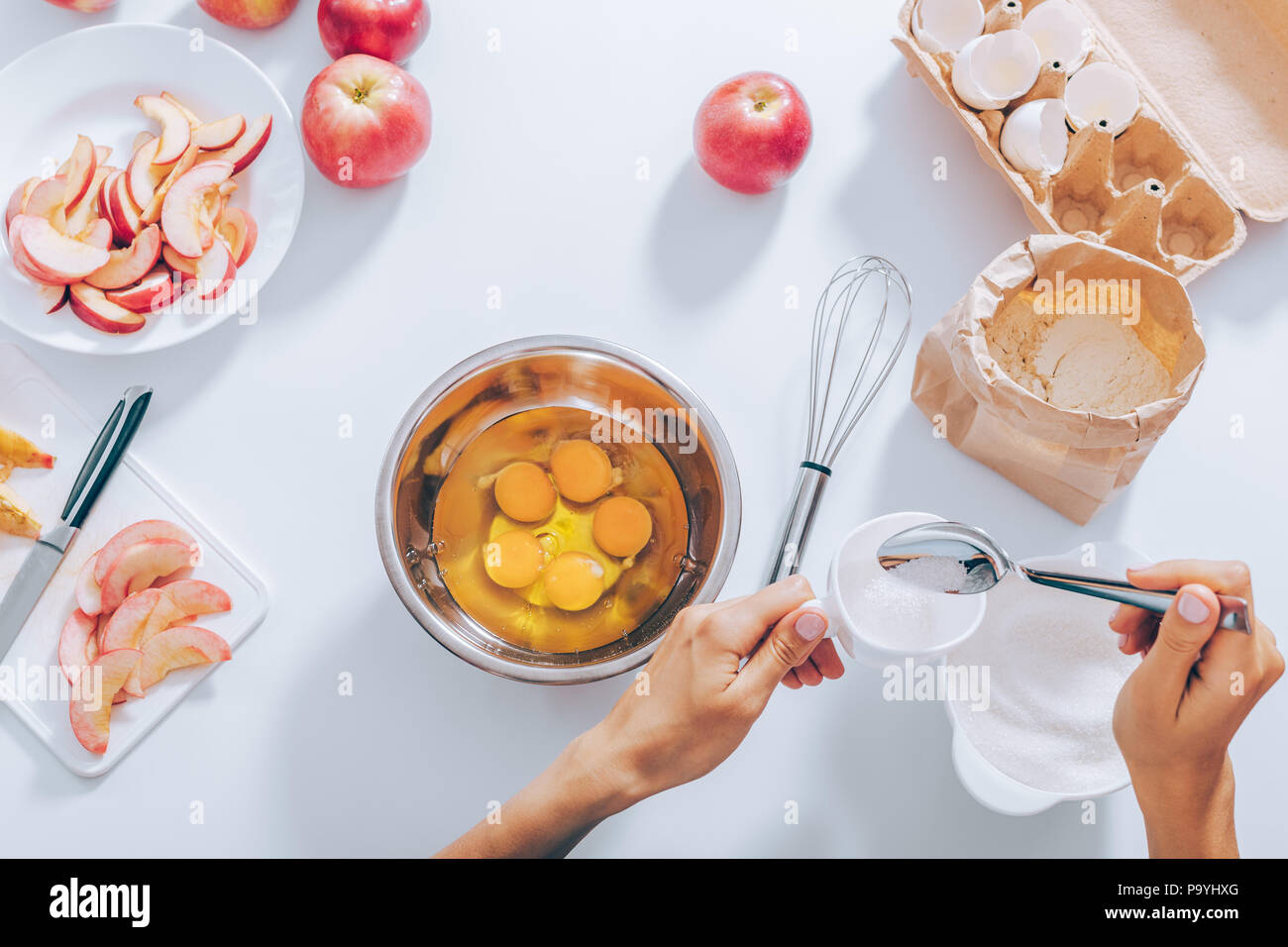 Woman's hands measuring cup of sugar to mix it with eggs next to  ingredients for baking apple pie, top view. Female cooking batter for cake  near cut f Stock Photo - Alamy