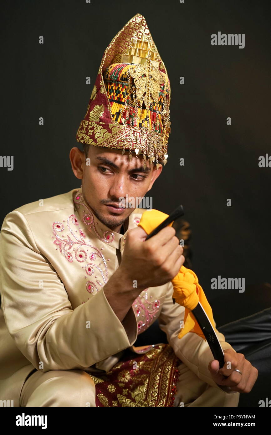 Handsome man in traditional acehnese dress holding Rencong (Traditional aceh weapon) Stock Photo