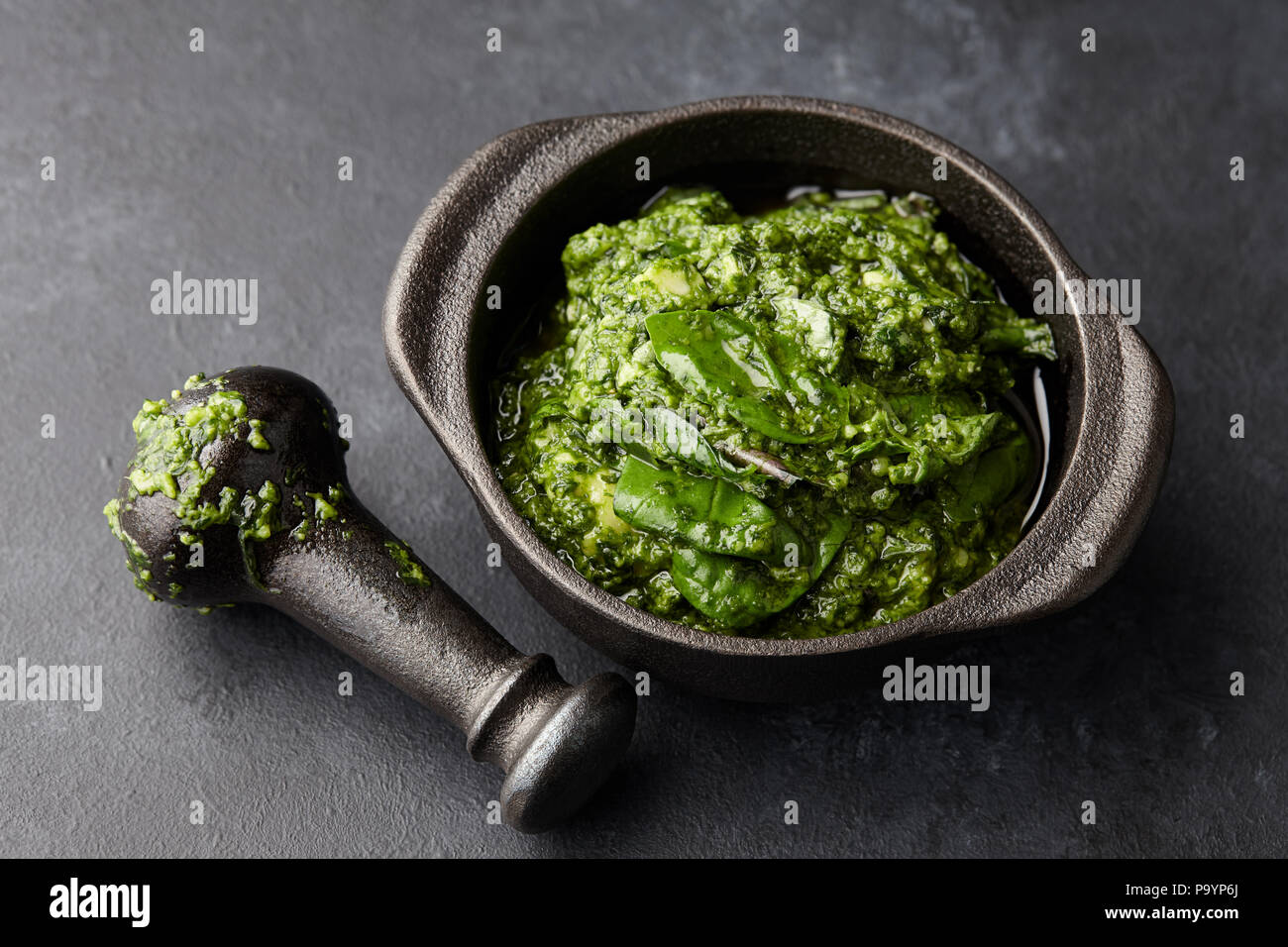 Basil pesto sauce in iron mortar, close up view Stock Photo