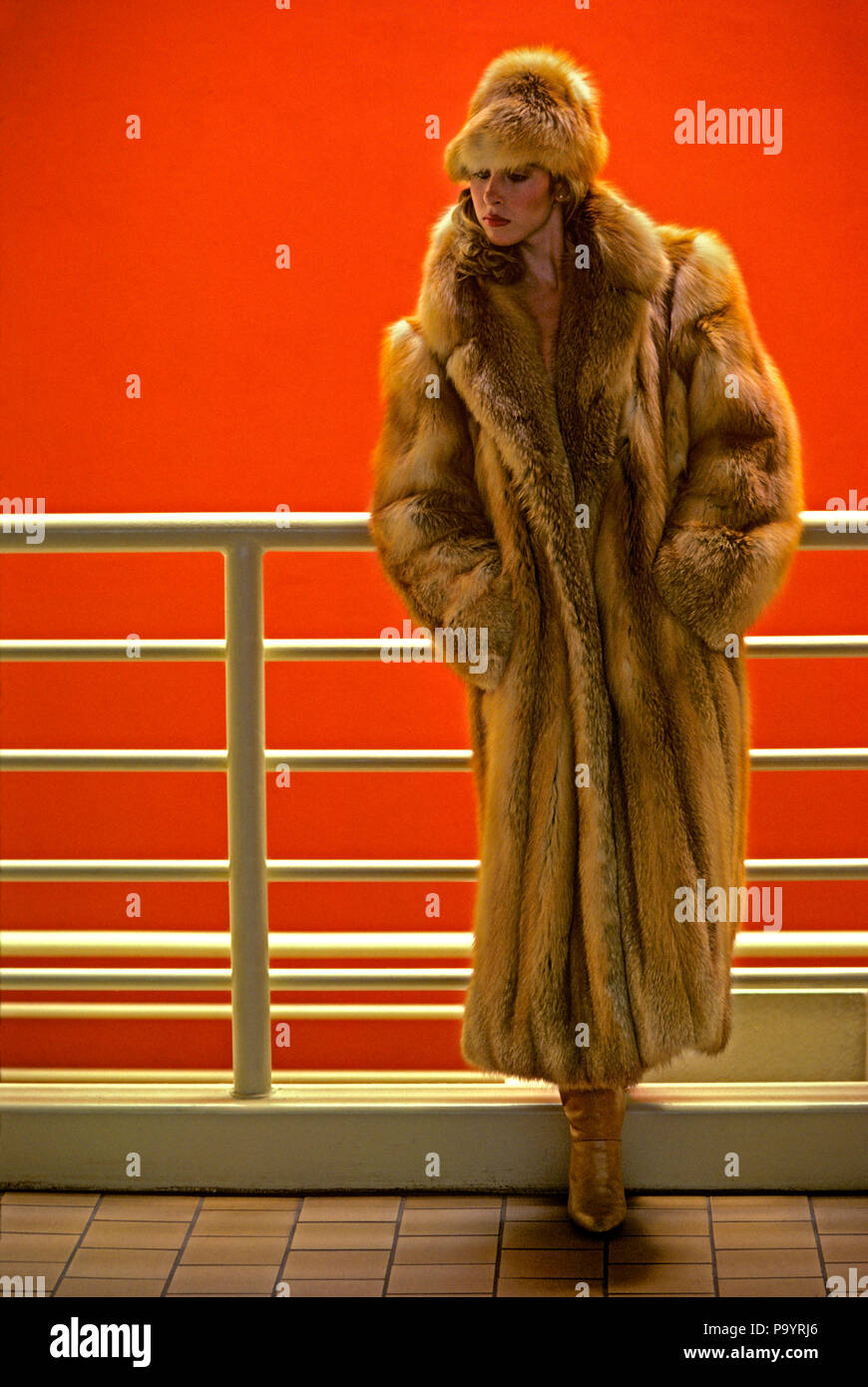 1980s WOMAN MODEL IN FUR COAT AND HAT STANDING BY WHITE RAILING  - 040038 TWE001 HARS FULL-LENGTH LADIES PERSONS GROWN-UP NORTH AMERICA NORTH AMERICAN PEOPLE STORY LEISURE STYLES RAILING OCCUPATIONS PELTS STYLISH FASHIONS FURS ROCKY MOUNTAINS YOUNG ADULT WOMAN CAUCASIAN ETHNICITY COLORADO GREAT PLAINS HEAD WARE OLD FASHIONED Stock Photo