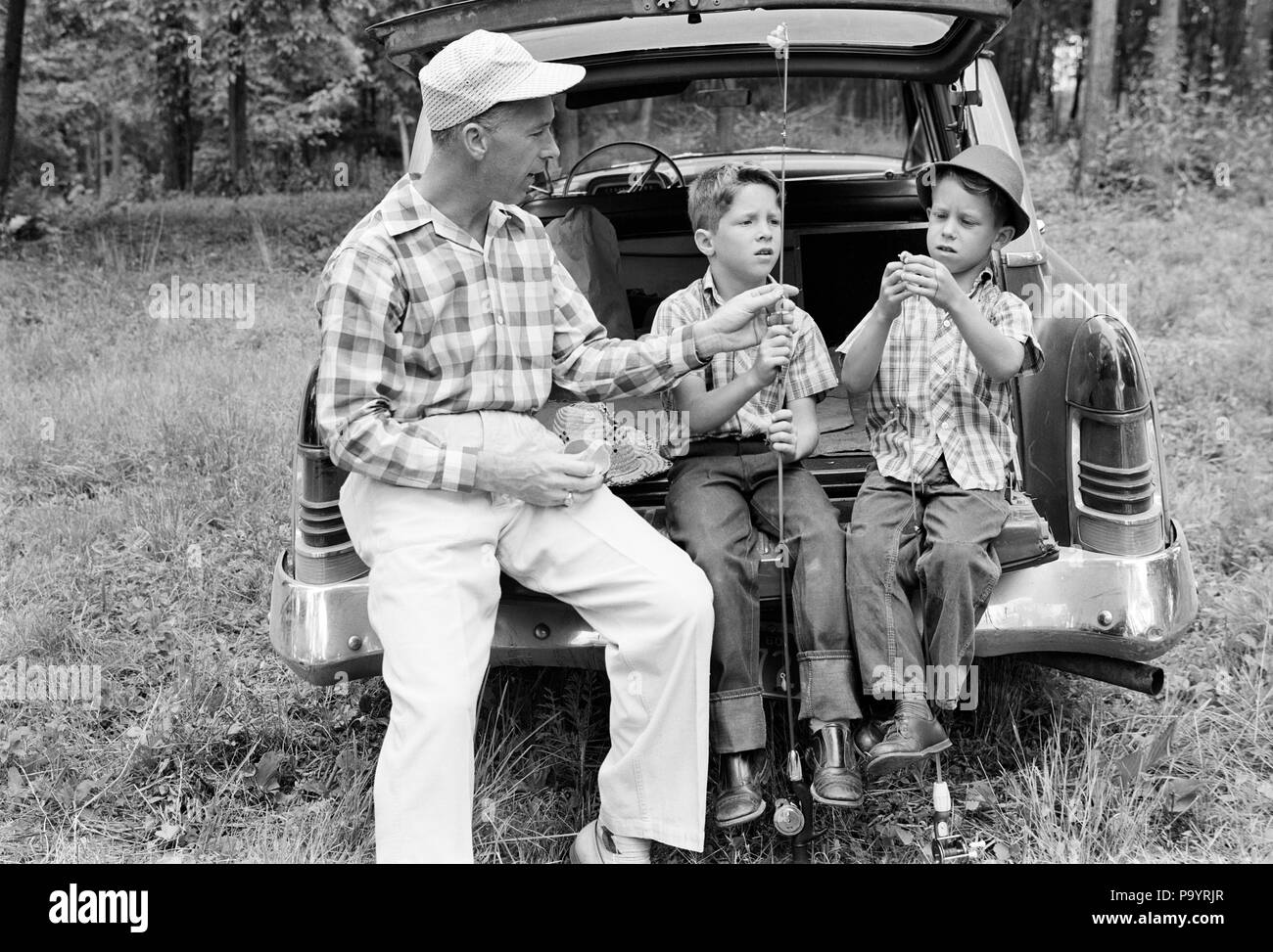1960s MAN FATHER AND TWO BOYS SONS TWINS SITTING ON REAR BUMPER OF CAR PREPARING FISHING GEAR - a2310 LAN001 HARS TEACHING NOSTALGIA GEAR BROTHER OLD FASHION AUTO 1 JUVENILE VEHICLE TEAMWORK TWIN VACATION SONS IDENTICAL DOUBLE FAMILIES JOY LIFESTYLE PARENTING BROTHERS SHOWING RURAL HEALTHINESS PREPARING FULL-LENGTH PERSONS INSPIRATION MATCH AUTOMOBILE CARING MALES SIBLINGS TRANSPORTATION FATHERS B&W FREEDOM MATCHING SAME TIME OFF HAPPINESS ADVENTURE AND AUTOS GETAWAY DADS KNOWLEDGE BUMPER ON AUTHORITY HOLIDAYS SIBLING INSTRUCTING CONNECTION AUTOMOBILES ESCAPE VEHICLES LOOK-ALIKE DUPLICATE Stock Photo