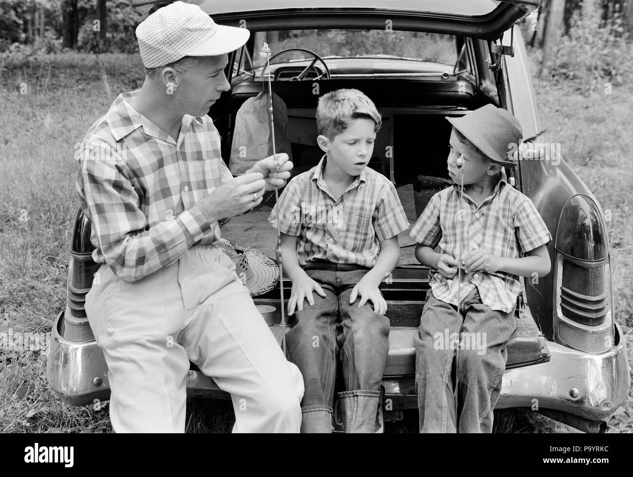 1960s MAN FATHER AND TWO BOYS SONS TWINS SITTING ON REAR BUMPER OF CAR PREPARING FISHING GEAR - a2316 LAN001 HARS TEACHING NOSTALGIA GEAR BROTHER OLD FASHION AUTO 1 JUVENILE VEHICLE TEAMWORK TWIN VACATION SONS IDENTICAL DOUBLE FAMILIES JOY LIFESTYLE PARENTING BROTHERS SHOWING RURAL HEALTHINESS PREPARING HALF-LENGTH PERSONS INSPIRATION MATCH AUTOMOBILE CARING MALES SIBLINGS TRANSPORTATION FATHERS B&W FREEDOM MATCHING SAME TIME OFF HAPPINESS ADVENTURE AND AUTOS GETAWAY DADS KNOWLEDGE BUMPER ON AUTHORITY HOLIDAYS SIBLING INSTRUCTING CONNECTION AUTOMOBILES ESCAPE VEHICLES LOOK-ALIKE DUPLICATE Stock Photo