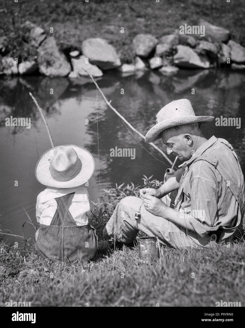 1930s GRANDFATHER AND GRANDSON WEARING STRAW HATS FISHING IN POND WITH STRING AND STICK RODS CAN OF WORMS FOR BAIT - a4685 HAR001 HARS GRANDFATHER GRANDPARENTS FAMILIES JOY LIFESTYLE ELDER GRANDPARENT RURAL HOME LIFE FRIENDSHIP HALF-LENGTH PERSONS MALES SENIOR MAN SENIOR ADULT B&W SUMMERTIME HAPPINESS OLDSTERS HIGH ANGLE OLDSTER ADVENTURE AND RECREATION YOUNG AND OLD ELDERS GRANDFATHERS GRANDSON ANGLING JUVENILES RODS TOGETHERNESS WORMS BAIT BLACK AND WHITE CAUCASIAN ETHNICITY GRANDPA HAR001 OLD FASHIONED Stock Photo