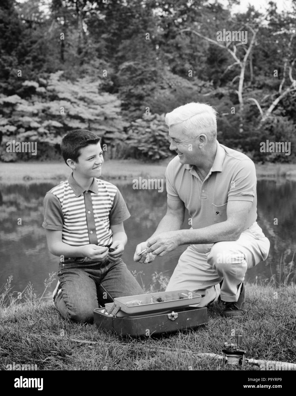 1960s GRANDFATHER AND GRANDSON SELECTING EQUIPMENT FROM A FISHING