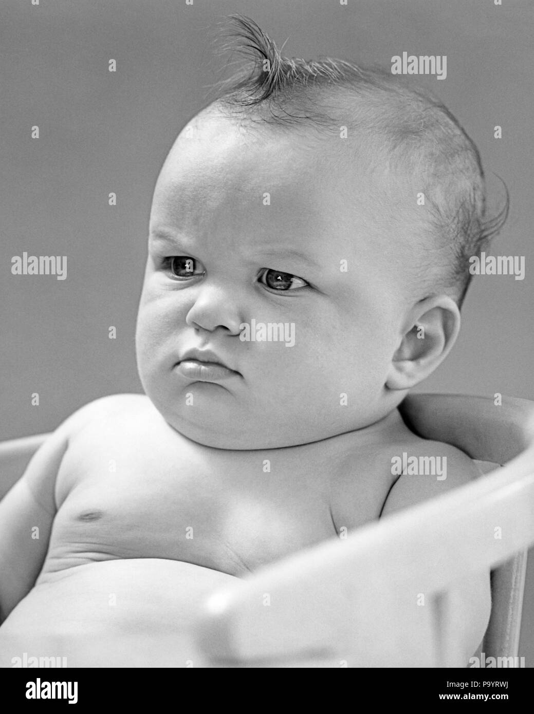 1940s PORTRAIT BABY FROWNING SCOWLING SITTING IN CHAIR - b10902 HAR001 HARS B&W FROWNING SADNESS MEAN ANXIOUS POUTING SCOWLING POUT BABY BOY CRABBY DIRTY LOOK DISGRUNTLED JUVENILES NASTY BLACK AND WHITE CAUCASIAN ETHNICITY DISLIKE HAR001 OLD FASHIONED Stock Photo