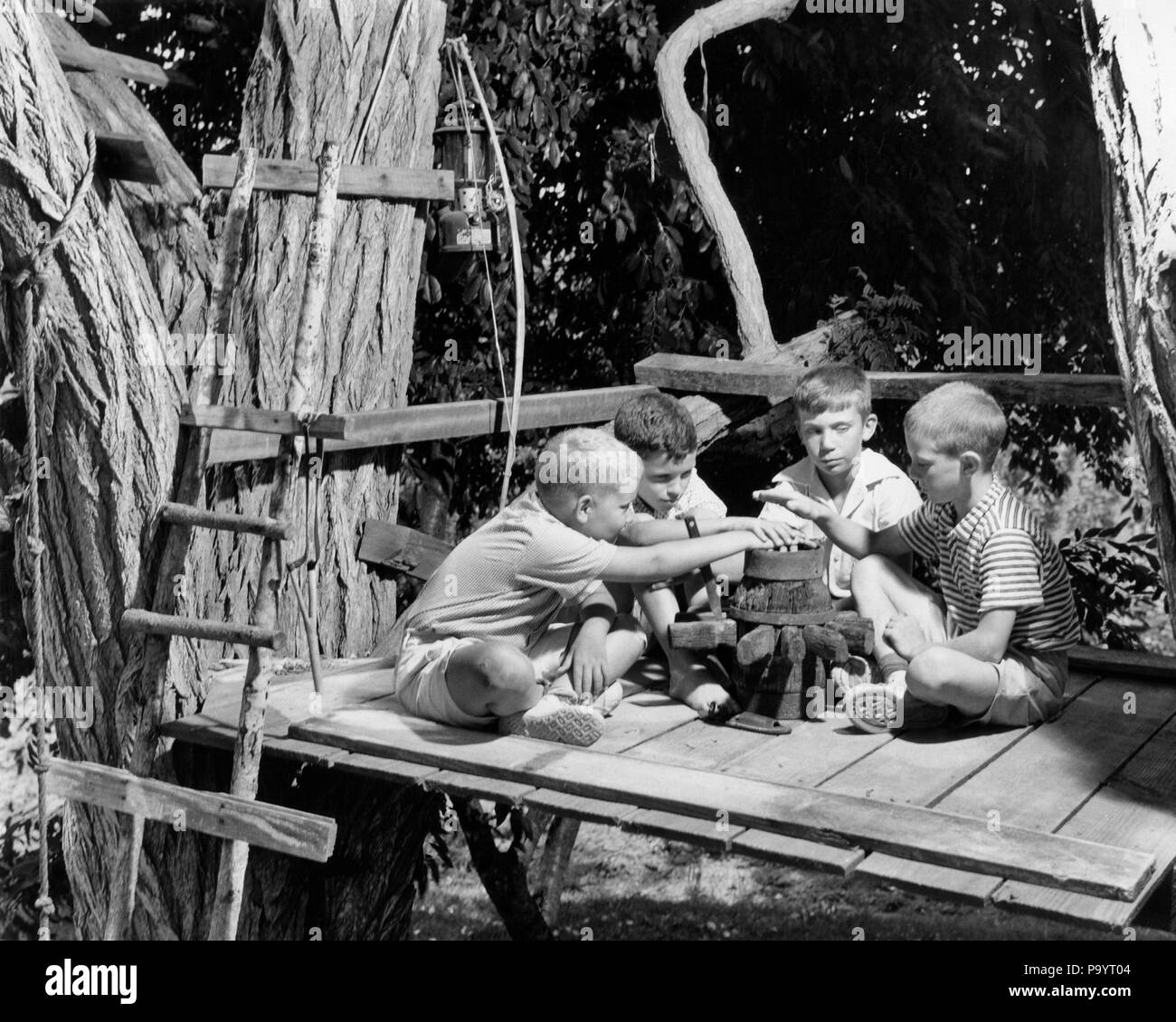 1950s 1960s FOUR BOYS IN TREE HOUSE CLUBHOUSE HOLDING HANDS OVER FAKE CAMPFIRE SWEARING TAKING OATH - b16212 CRS001 HARS EXCITEMENT CONNECTION OATH CLUBHOUSE IMAGINATION SWEARING GROWTH JUVENILES PRE-TEEN PRE-TEEN BOY TOGETHERNESS BLACK AND WHITE CAUCASIAN ETHNICITY OLD FASHIONED TREE HOUSE Stock Photo