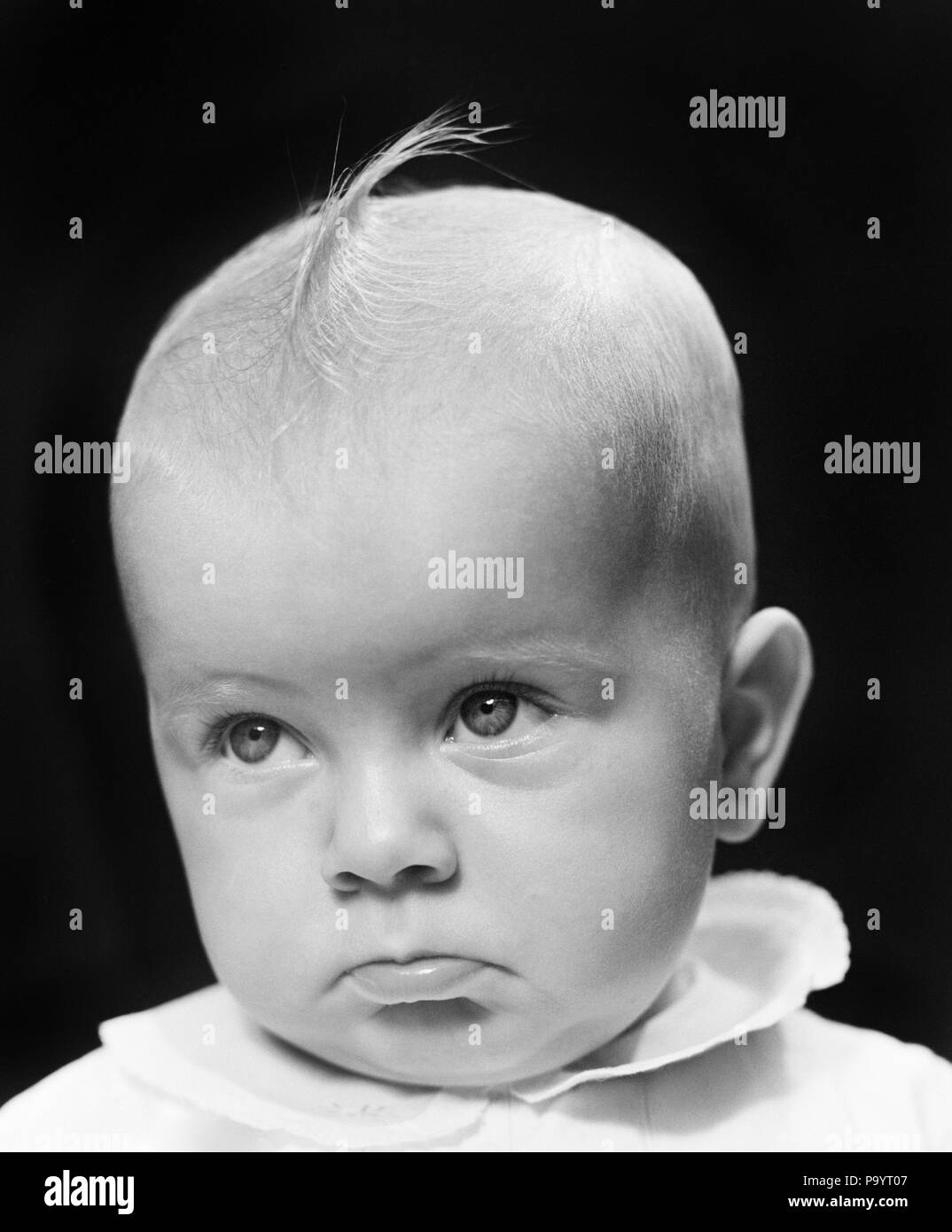 1940s BABY GIRL WITH TUFT OF BLONDE HAIR LOOKING VERY SAD - b165 HAR001 HARS VERY HEAD AND SHOULDERS POUTING CONCEPTUAL FORLORN POUT TUFT EMOTION JUVENILES MISERABLE BABY GIRL BLACK AND WHITE HAR001 OLD FASHIONED Stock Photo