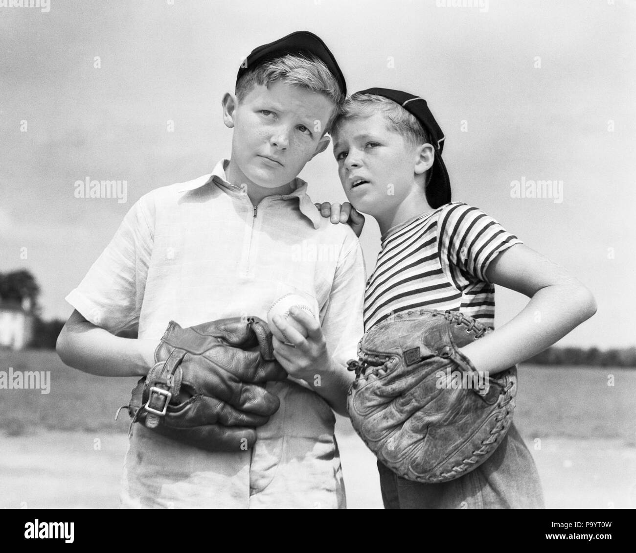 1930s TWO BOYS WEARING BASEBALL CAPS AND GLOVES CATCHER AND PITCHER PLANNING STRATEGY WHISPERING - b1990 HAR001 HARS HEALTHINESS COPY SPACE HALF-LENGTH MALES PLANNING SIBLINGS EXPRESSIONS B&W SUMMERTIME GOALS PITCHER HAPPINESS STRATEGY CATCHER MITT AND RECREATION MITTS SIBLING CONNECTION CAPS BALL GAME BALL SPORT COOPERATION JUVENILES BLACK AND WHITE CAUCASIAN ETHNICITY HAR001 OLD FASHIONED Stock Photo