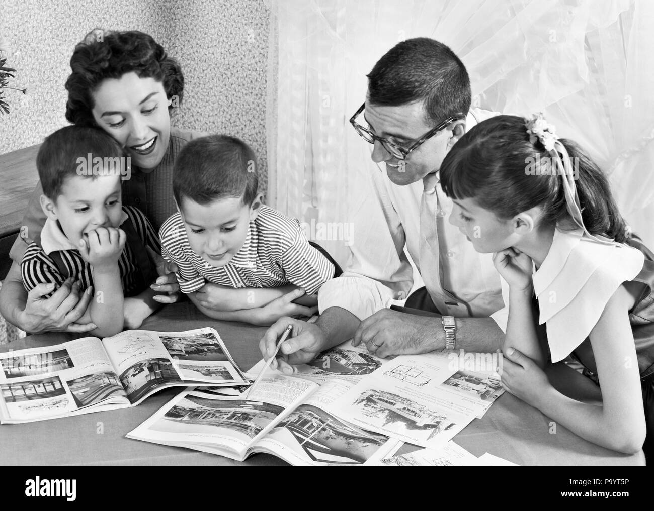 1950s FAMILY OF FIVE READING MAGAZINES BOOKS ON DINING ROOM TABLE - bx017281 CAM001 HARS NOSTALGIC PAIR RELATIONSHIP MOTHERS STUDY OLD TIME NOSTALGIA BROTHER HOMEWORK OLD FASHION SISTER 1 JUVENILE SONS PLEASED FAMILIES JOY FIVE PARENTING FEMALES 5 BROTHERS HUSBANDS HORIZONTAL PLANS DAUGHTERS PERSONS MALES SIBLINGS SISTERS FATHERS HUSBAND AND WIFE B&W HUSBANDS AND WIVES CHEERFUL DADS CAM001 SIBLING SMILES JOYFUL JUVENILES MOMS WIVES BLACK AND WHITE CAUCASIAN ETHNICITY OLD FASHIONED Stock Photo