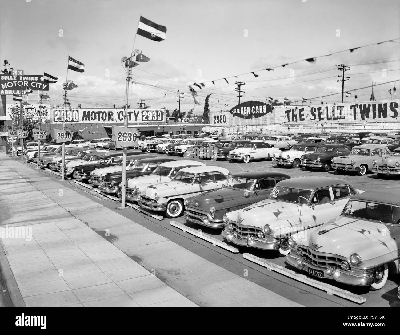 1950s 1960s SIGNS AND FLAGS AT CAR DEALERSHIP ROWS OF NEW CARS FOR SALE - by007776 CAM001 HARS OLD FASHIONED Stock Photo