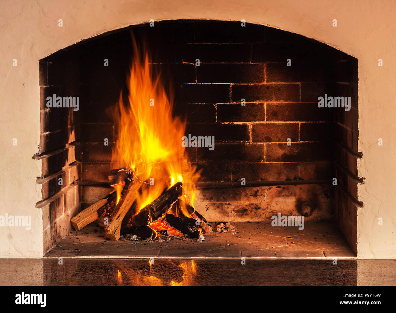 Fire in a home fireplace with reflection on a stone. Evening light Stock Photo