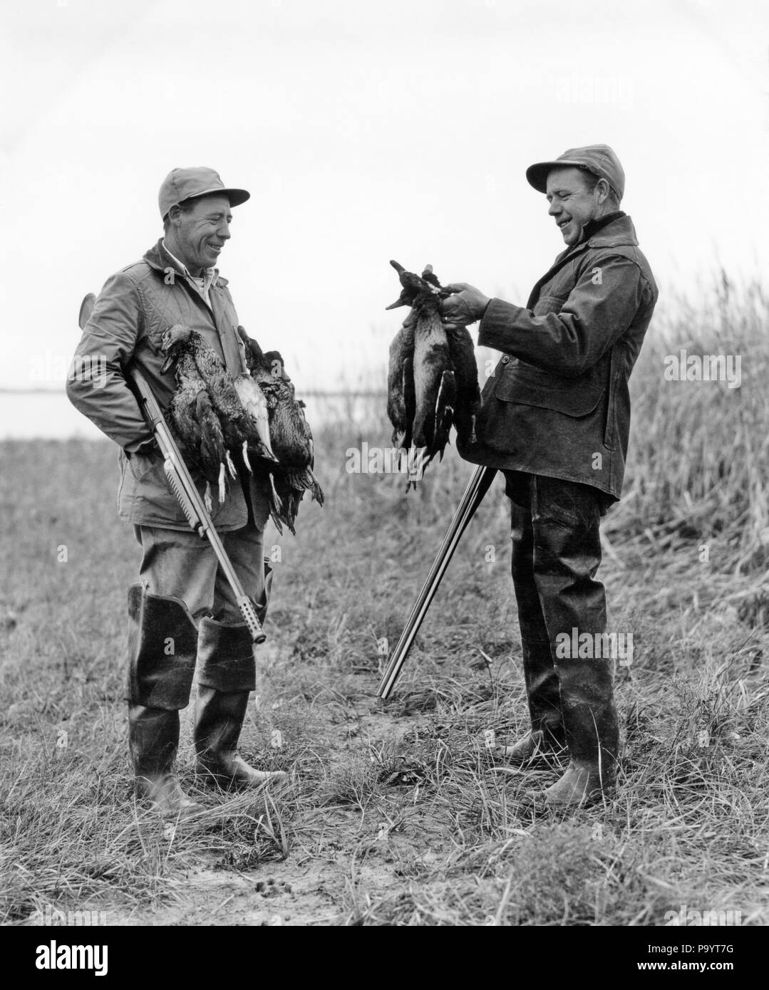 1950s TWO MEN DUCK HUNTERS WITH SHOTGUNS ADMIRING A BRACE OF DUCKS - d3806 HAR001 HARS MID-ADULT MAN SHOTGUNS TOGETHERNESS ADMIRING BLACK AND WHITE BRACE CAUCASIAN ETHNICITY HAR001 OLD FASHIONED Stock Photo