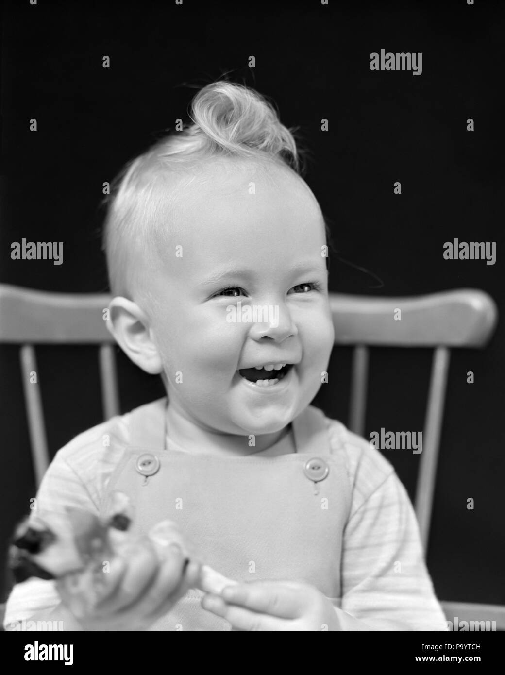 1940s PORTRAIT SMILING BABY SITTING IN WINDSOR STYLE CHAIR HOLDING TOY - j9245 HAR001 HARS CHEERFUL IN SMILES JOYFUL BABY BOY WINDSOR CURL JUVENILES KEWPIE DOLL BLACK AND WHITE CAUCASIAN ETHNICITY HAR001 OLD FASHIONED Stock Photo