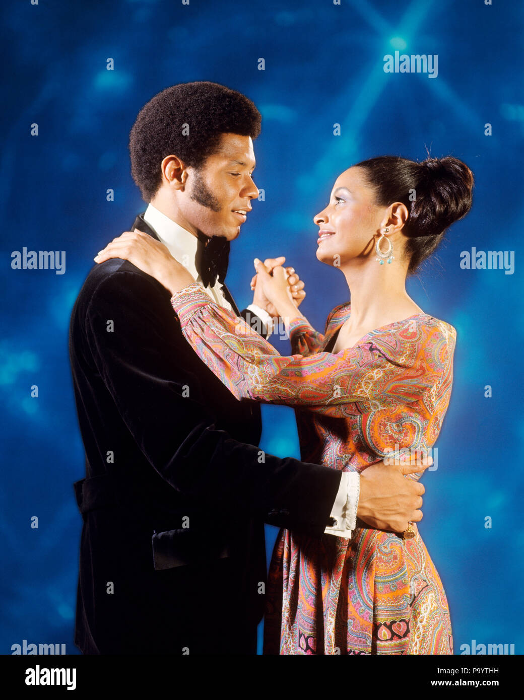1970s AFRICAN AMERICAN COUPLE IN EVENING DRESS SLOW DANCING TOGETHER