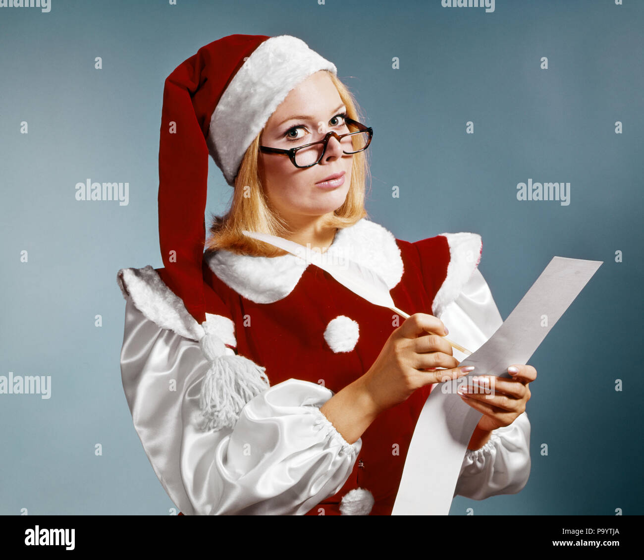 1960s WOMAN IN CHRISTMAS SANTA'S HELPER COSTUME AND CAP WEARING GLASSES LOOKING AT CAMERA CHECKING NAUGHTY OR NICE LIST - kg2929 HAR001 HARS QUILL INFORMATION ASSISTANT CHECKING LIFESTYLE FEMALES STUDIO SHOT COPY SPACE HALF-LENGTH LADIES PERSONS CHARACTER EYEGLASSES EXPRESSIONS MIDDLE-AGED EYE CONTACT NICE AND HELPER AUTHORITY OCCUPATIONS ELF SANTA'S STYLISH OR MID-ADULT TWICE CAUCASIAN ETHNICITY HAR001 OLD FASHIONED Stock Photo