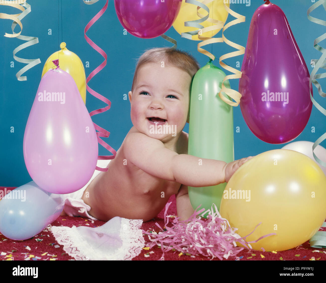 1960s BABY GIRL HUGGING BALLOON CONFETTI STREAMERS SMILING HAPPY  - kn377 HAR001 HARS EXPRESSIONS EYE CONTACT HAPPINESS CHEERFUL EXCITEMENT OCCUPATIONS PARTIES SMILES JOYFUL GROWTH JUVENILES BABY GIRL CAUCASIAN ETHNICITY HAR001 OLD FASHIONED Stock Photo