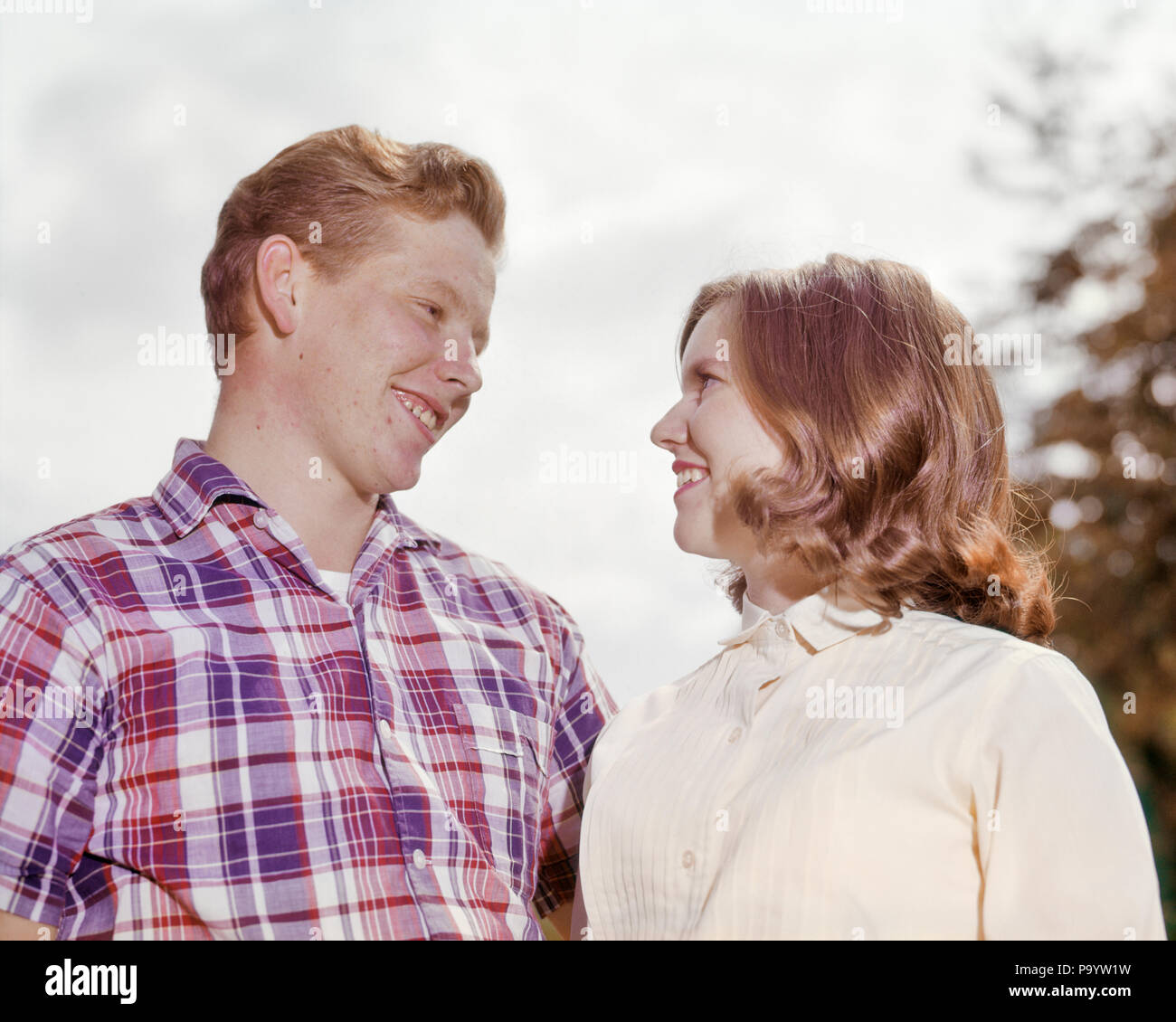 1960s SMILING YOUNG TEENAGE COUPLE LOOKING AT EACH OTHER ROMANTICALLY - kp1245 HAR001 HARS COMMUNICATION BALANCE MYSTERY PLEASED JOY LIFESTYLE FEMALES HOME LIFE COPY SPACE FRIENDSHIP HALF-LENGTH ADOLESCENT PERSONS CARING MALES TEENAGE GIRL TEENAGE BOY EXPRESSIONS HAPPINESS HEAD AND SHOULDERS CHEERFUL EXCITEMENT LOW ANGLE REDHEAD SMILES CONNECTION RED HAIR JOYFUL TEENAGED GROWTH JUVENILES ROMANTICALLY CAUCASIAN ETHNICITY HAR001 OLD FASHIONED Stock Photo