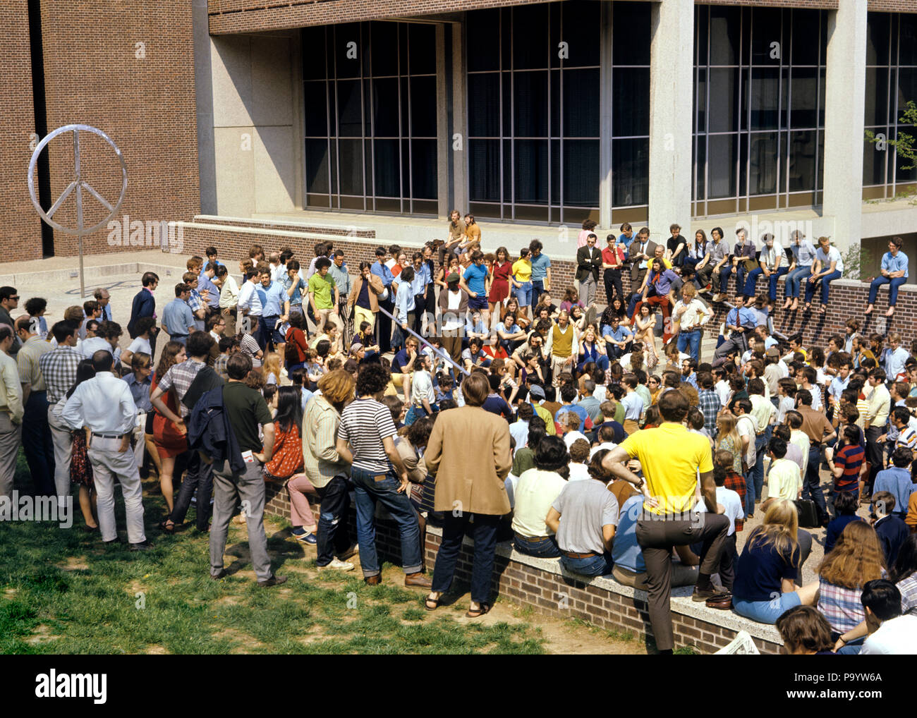 1960s 1970s GROUP OF ANTI-WAR STUDENT PROTESTERS GATHERING DEMONSTRATING NEAR PEACE SIGN  - ks7126 HAR001 HARS REPRESENTATION Stock Photo