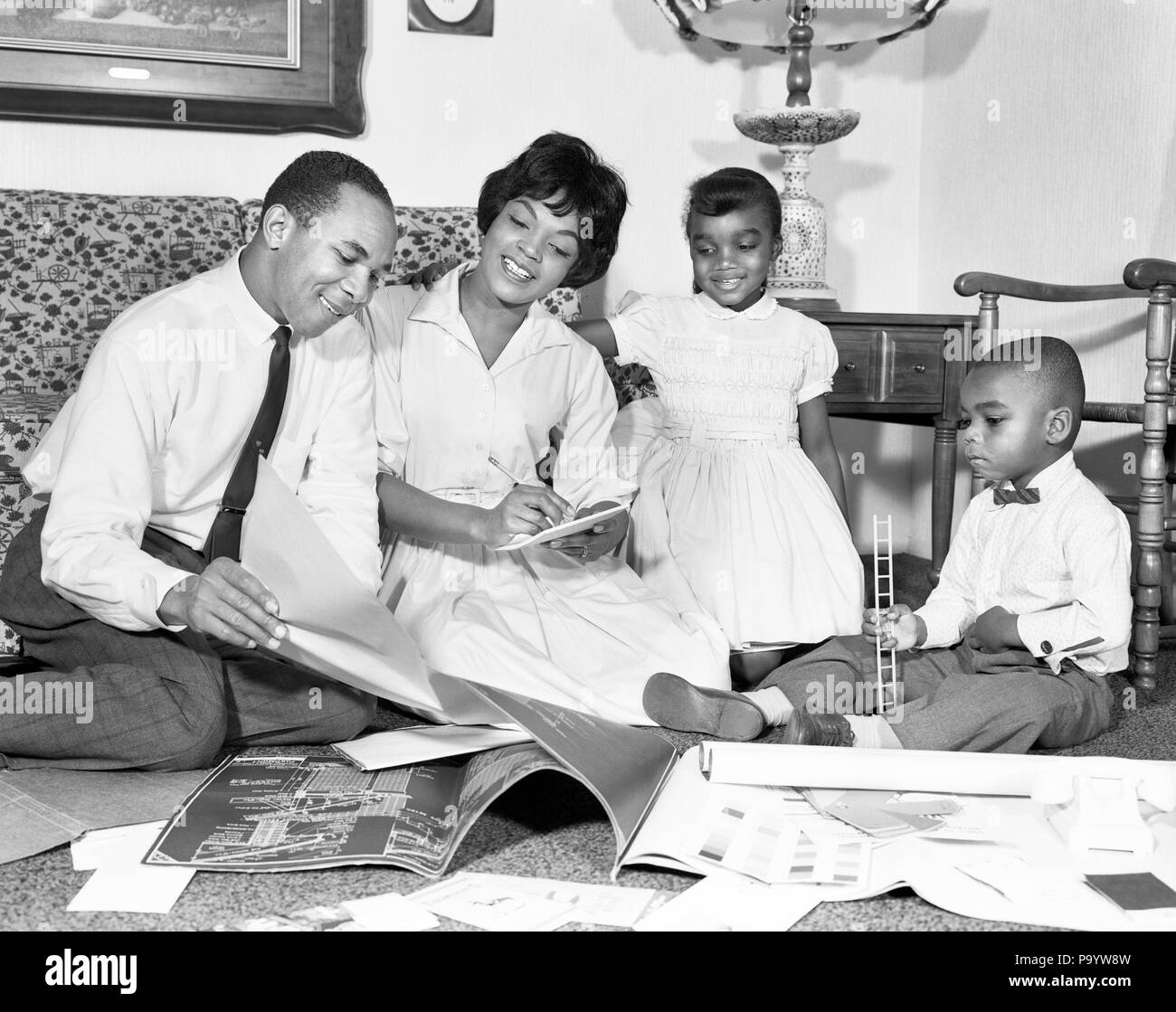 1960s AFRICAN AMERICAN FAMILY LOOKING AT BLUEPRINTS PLANNING FOR A NEW HOME BOY GIRL MOTHER FATHER - n1826 HAR001 HARS SISTER JUVENILE TEAMWORK INFORMATION SONS JOY LIFESTYLE FEMALES BROTHERS HOME LIFE HALF-LENGTH DAUGHTERS INSPIRATION MALES PLANNING SIBLINGS SISTERS BLUEPRINTS FATHERS B&W DREAMS HAPPINESS ADVENTURE AFRICAN-AMERICANS AFRICAN-AMERICAN CHOICE DADS EXCITEMENT BLACK ETHNICITY DIRECTION AT SIBLING COOPERATION GROWTH IDEAS JUVENILES MID-ADULT MID-ADULT MAN MID-ADULT WOMAN MOMS SOLUTIONS TOGETHERNESS BLACK AND WHITE HAR001 OLD FASHIONED AFRICAN AMERICANS Stock Photo