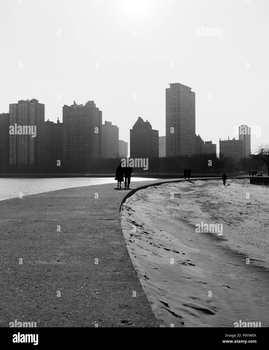 1960s TWO ANONYMOUS SILHOUETTED PEOPLE WALKING ALONG LAKE SHORE CHICAGO ILLINOIS USA - r20450 HAR001 HARS SUPPORT WINDY EDIFICE ANONYMOUS ILLINOIS TOGETHERNESS BLACK AND WHITE HAR001 IL LAKE MICHIGAN OLD FASHIONED Stock Photo