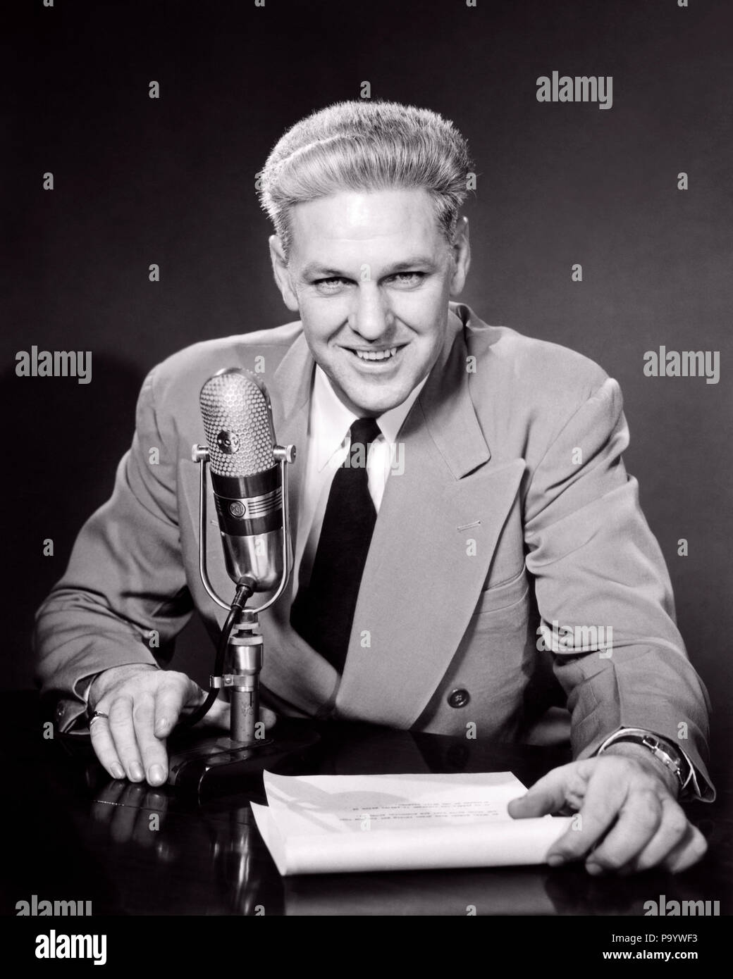 1950s SMILING MIDDLE AGED MAN NEWSMAN ANNOUNCER  TALKING INTO MICROPHONE LOOKING AT CAMERA - r4379 HAR001 HARS FACIAL STYLE COMMUNICATION BLOND COMPETITION PLEASED JOY LIFESTYLE JOBS HALF-LENGTH PERSONS MALES ENTERTAINMENT CONFIDENCE EXPRESSIONS B&W EYE CONTACT FREEDOM PERFORMING ARTS SKILL SUIT AND TIE OCCUPATION SKILLS CHEERFUL ANNOUNCER HONEST EXCITEMENT KNOWLEDGE AUTHORITY OCCUPATIONS POLITICS SMILES CONNECTION JOYFUL REPORTING STYLISH TRUSTWORTHY WIDE LAPELS SINCERE MID-ADULT MID-ADULT MAN NEWSMAN ANNOUNCING BLACK AND WHITE CAUCASIAN ETHNICITY COMMENTATOR HAR001 OLD FASHIONED Stock Photo