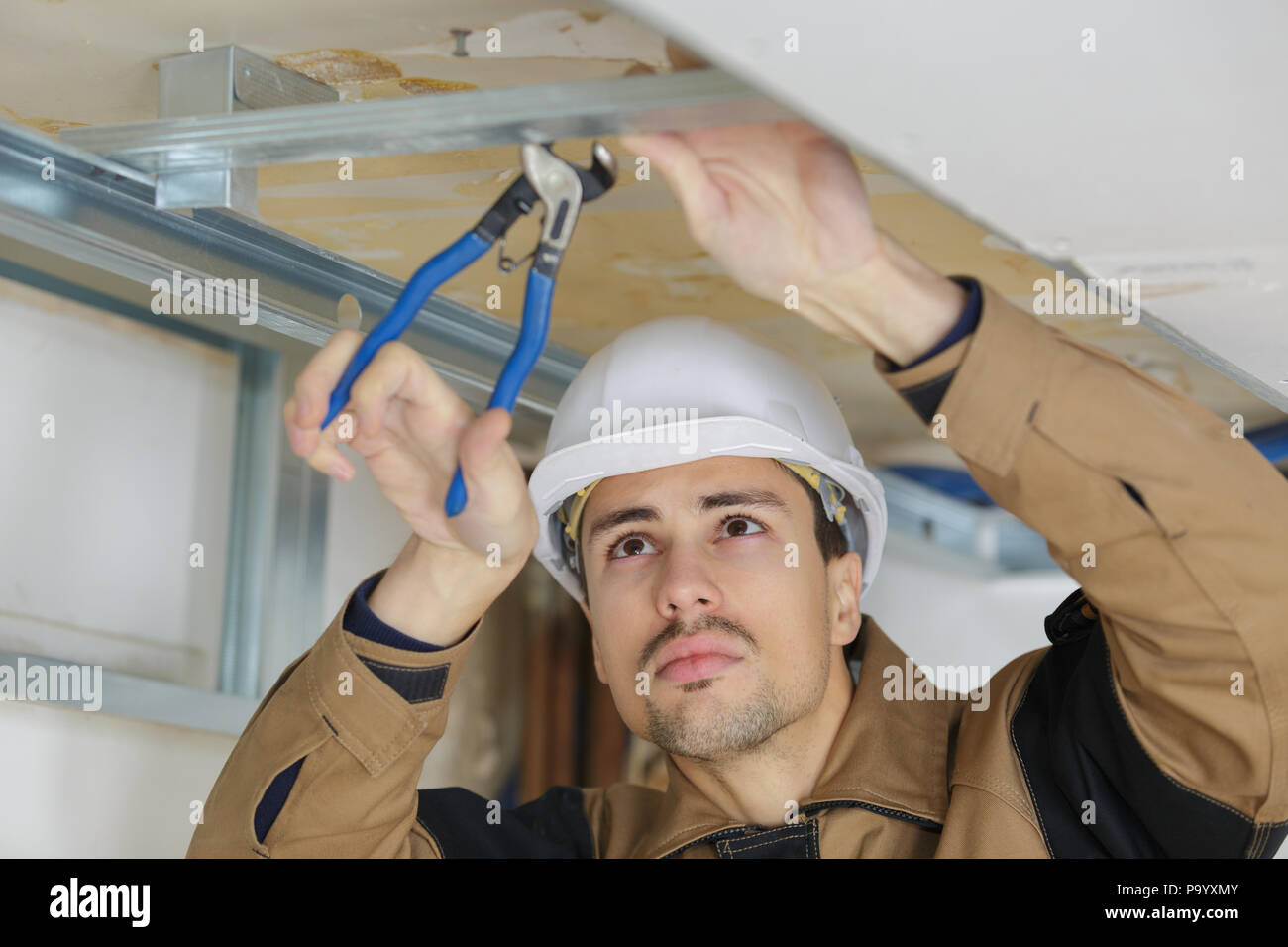 Workman using pliers on metal framework Stock Photo Alamy