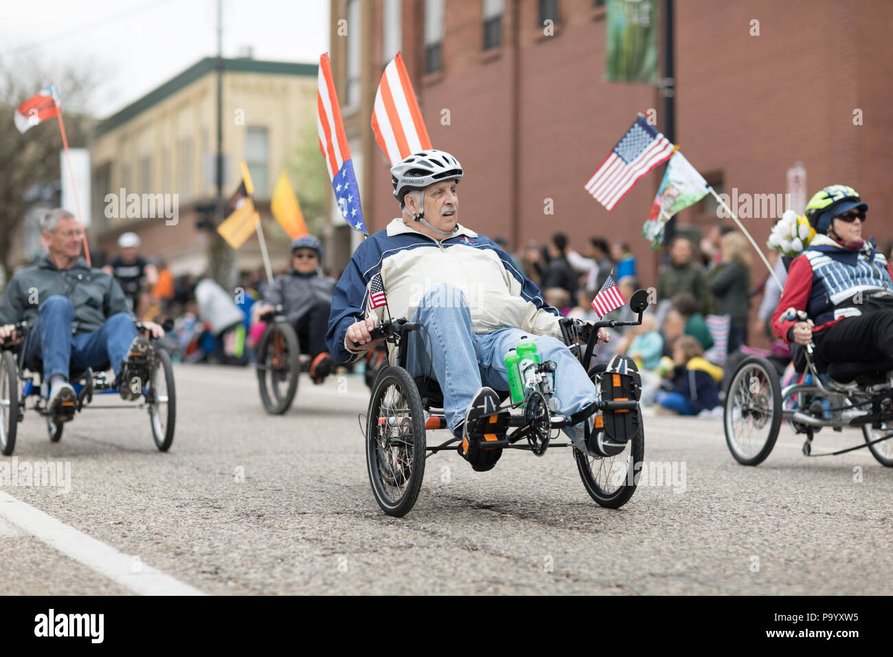 Holland, Michigan, USA - May 12, 2018 People riding trikes down the road at the Muziek Parade, during the Tulip Time Festival Stock Photo