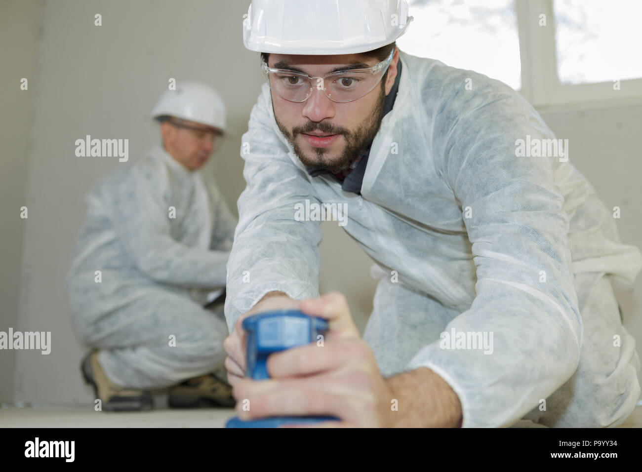 worker using a handheld belt sander Stock Photo Alamy