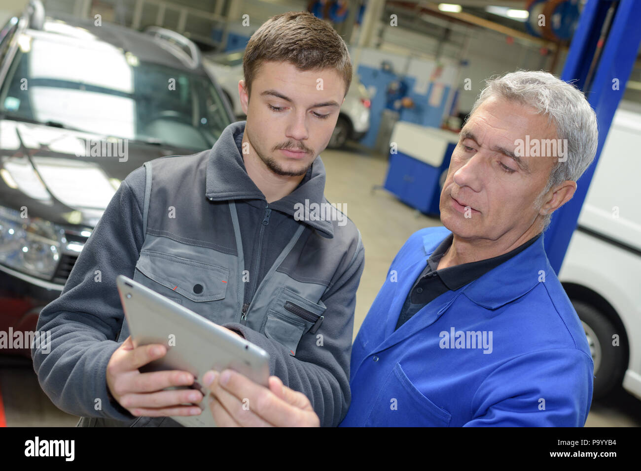 mechanics teacher with student in car repairshop Stock Photo