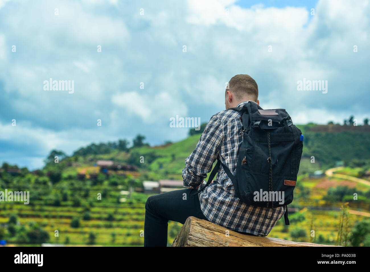 Portrait of man sitting on the mountain with backpack, Young man traveler with a backpack. Stock Photo