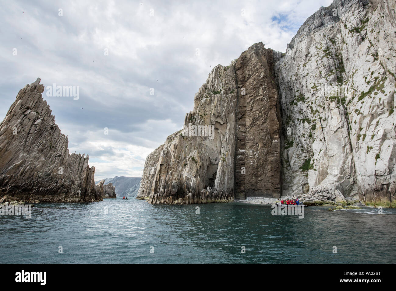 Zodiac with tourist travelling around a coastal landscape and rock formations in Chukotka Stock Photo