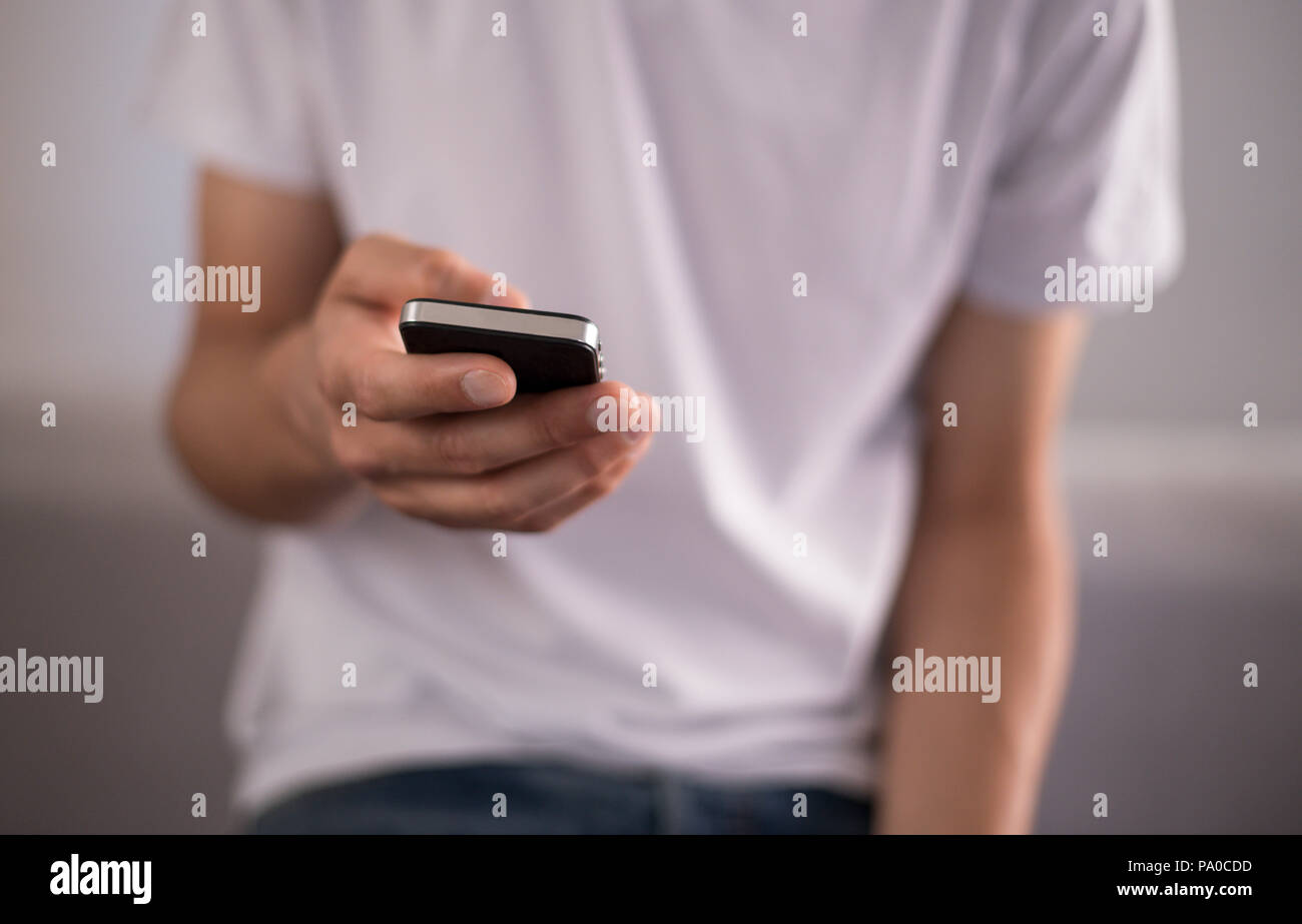 Young man using a touchscreen smartphone - Hands close-up - Using technology Stock Photo