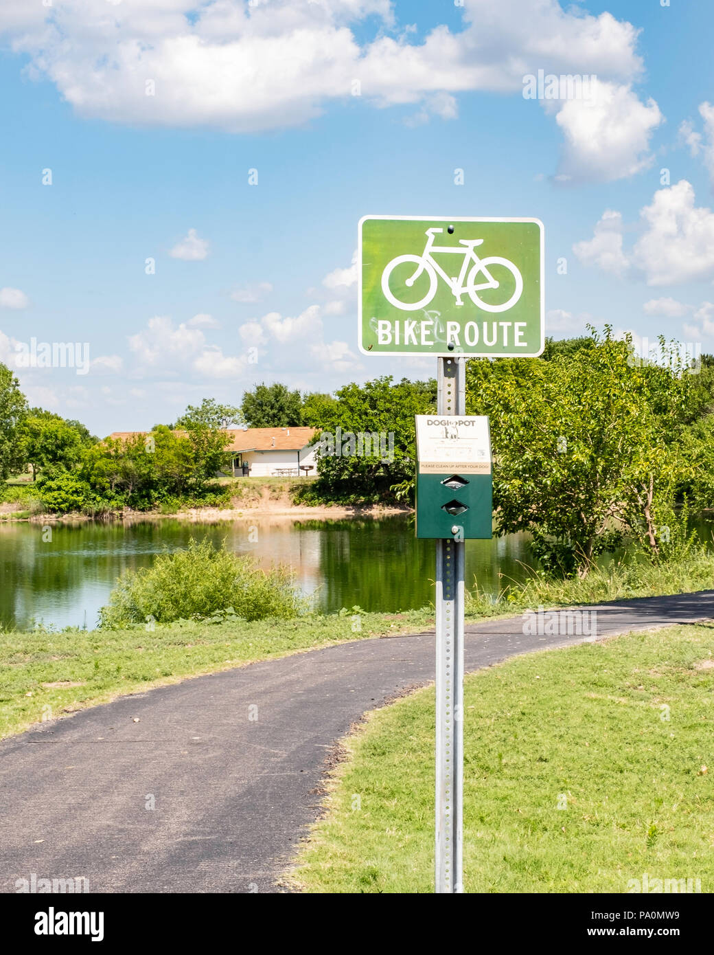 A bike route sign by a path and pond in Sedgwick county park, Wichita, Kansas, USA. Stock Photo