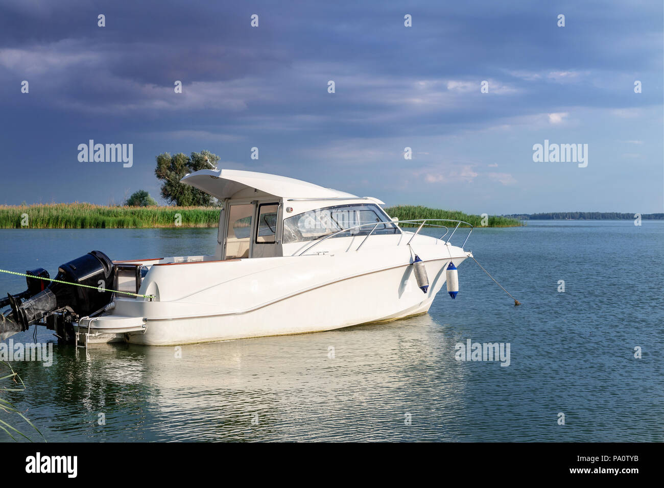 Luxury fishing motor boat moored at coast in bay on river or lake. Dark stormy sky with thunder clouds on background. Travel and recreation , bad weat Stock Photo