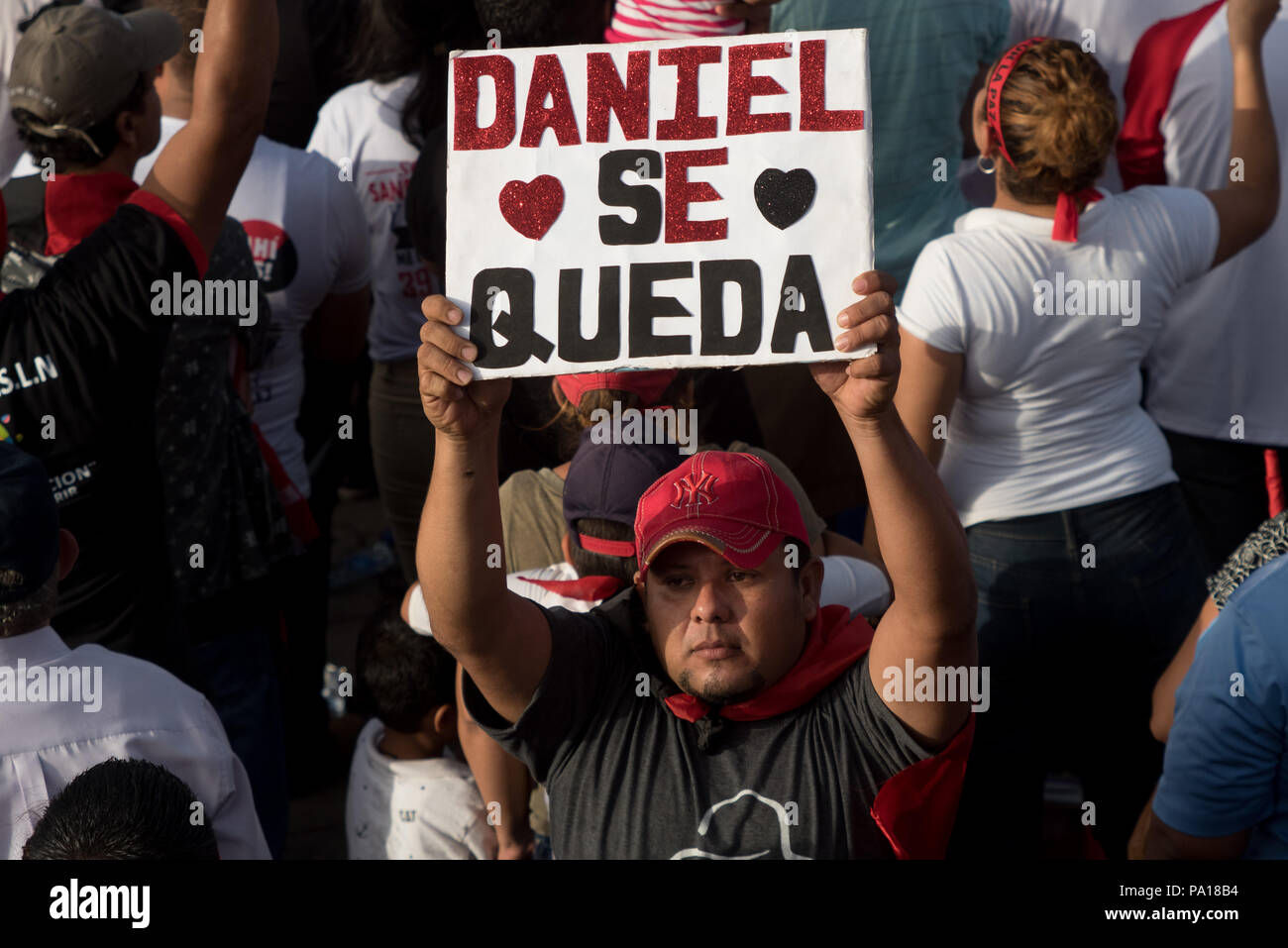 Managua, Nicaragua. 19th July, 2018. A supporter of the Sandinista National Liberation Front (FSLN) holding a sign with the text 'Daniel stays' during an event in conmemoration of the 39th anniversary of the Sandinista revolution. The Nicaraguan president has accused the country's Catholic church of being part of an attempted coup against his government. According to Ortega, the country's Catholic bishops aren't intermediaries in the political crisis, but rather part of a putschist conspiracy. Credit: Carlos Herrera/dpa/Alamy Live News Stock Photo