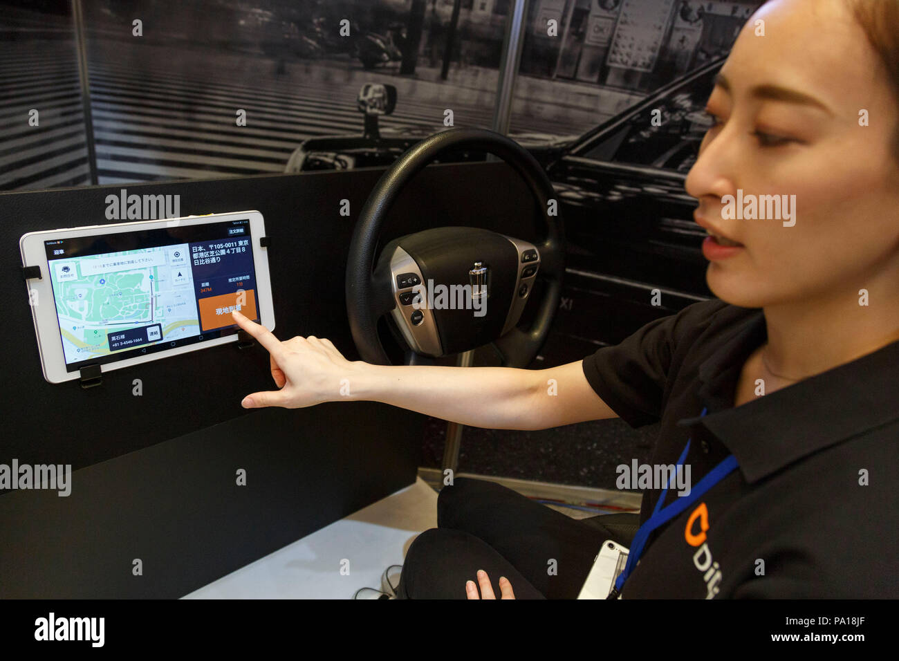 An exhibitor gives a demonstration of Didi Mobility Japan app during the SoftBank World 2018 on July 20, 2018, Tokyo, Japan. SoftBank World 2018 showcases companies working with AI (Artificial Intelligence) and in IoT (the Internet of Things), developing the latest applications for robots in various business fields. The show runs until July 20. Credit: Rodrigo Reyes Marin/AFLO/Alamy Live News Stock Photo