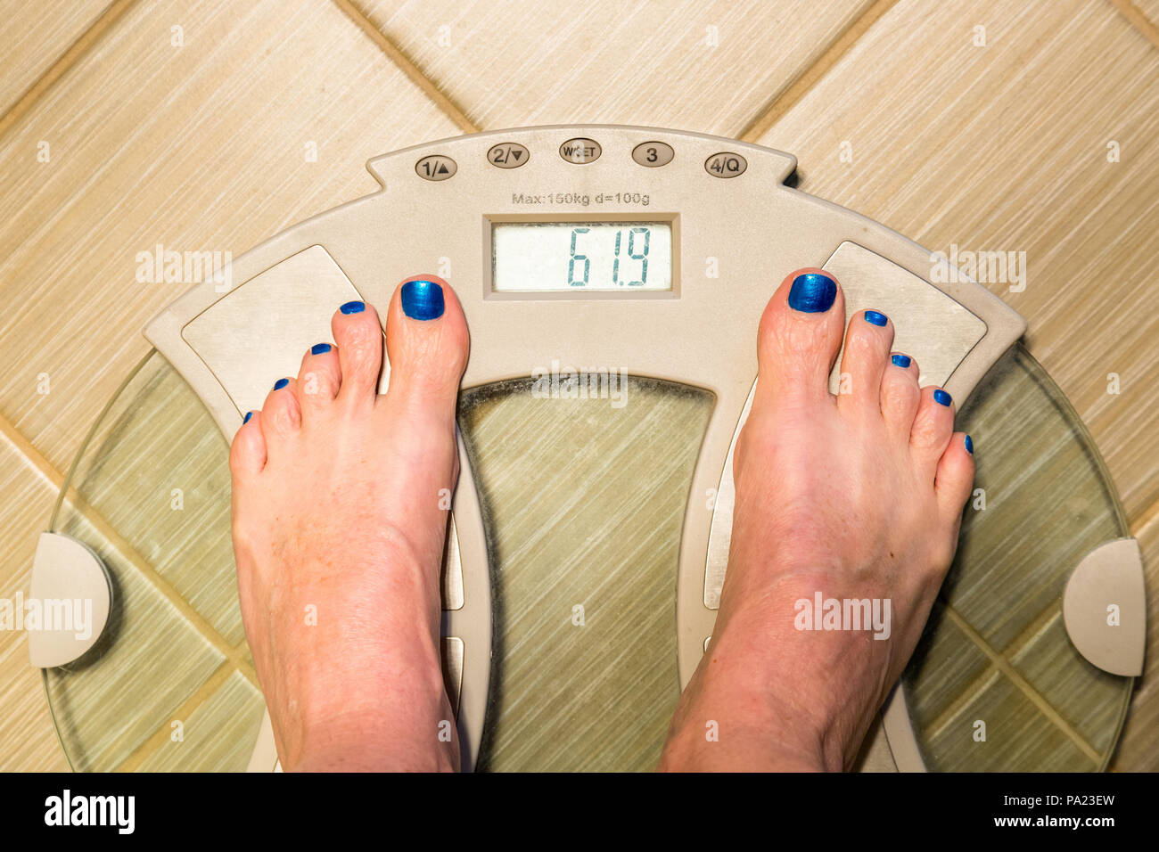 Female with bright blue nail polish on bathroom scales Stock Photo Alamy