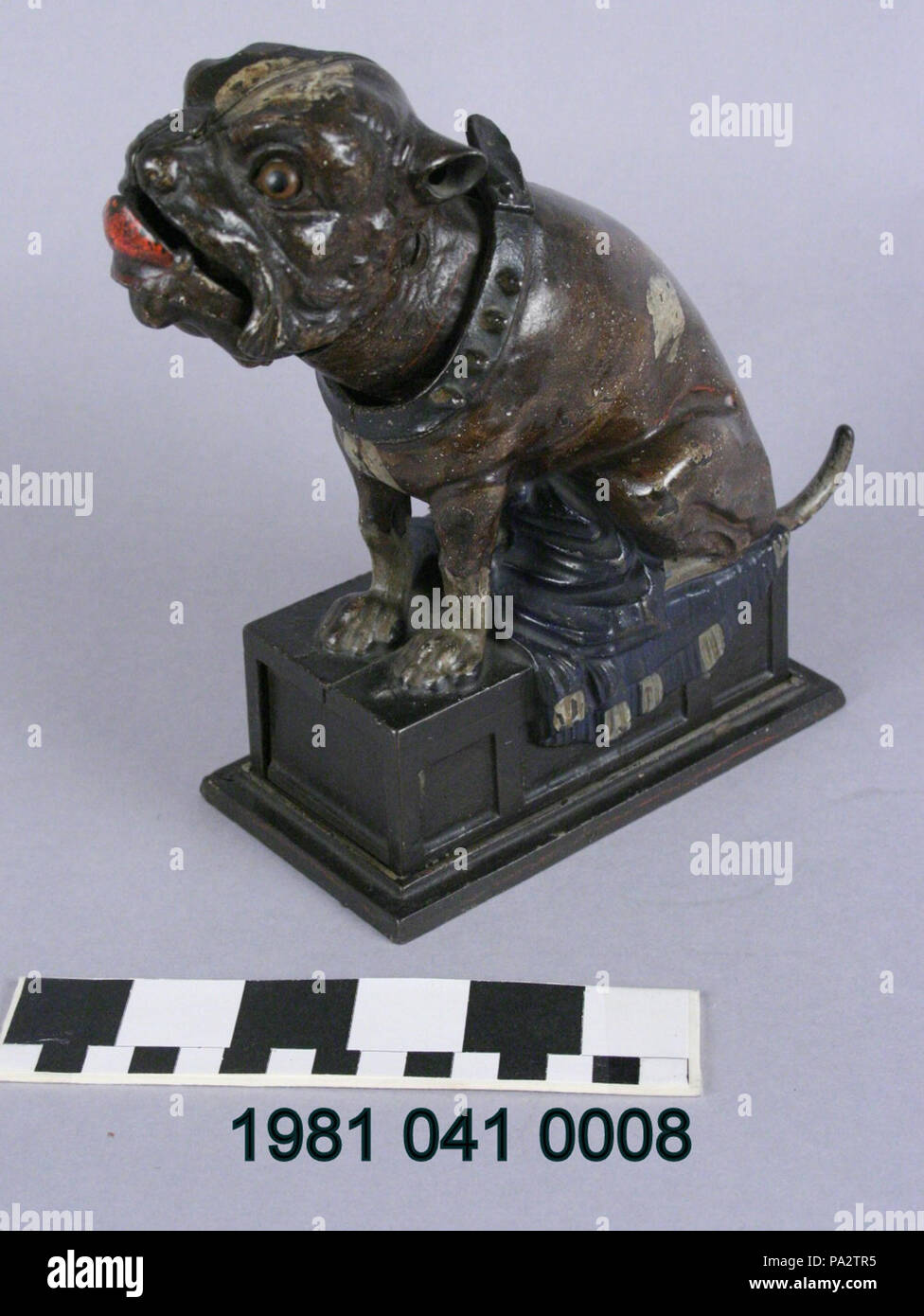 . English: Cast iron mechanical bank in the shape of a bull dog on top of a rectangular base. To make a deposit, a coin is placed on the dog's nose; pulling the dog's tail causes the dog to toss the coin off his nose and then catch it in his mouth, sending the coin to the reservoir below.Manufactured by the J and E Stevens Company circa 1880. Title: Bull Dog Mechanical Coin Bank . circa 1880 257 Bull Dog Mechanical Coin Bank Stock Photo