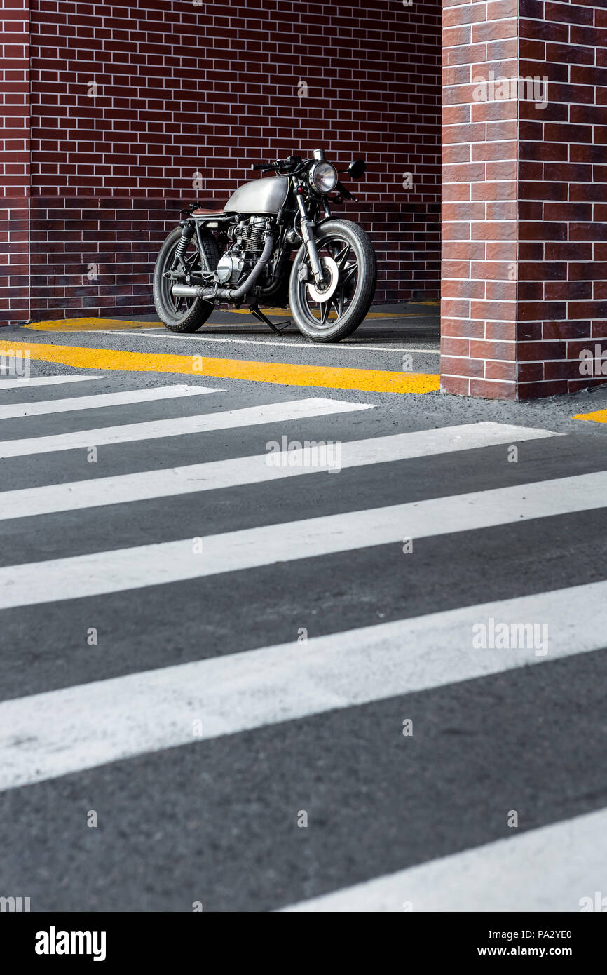 Caferacer motorcyle parking near brick wall of industrial building. Everything is ready for having fun after hard day in office. Businessman city hips Stock Photo