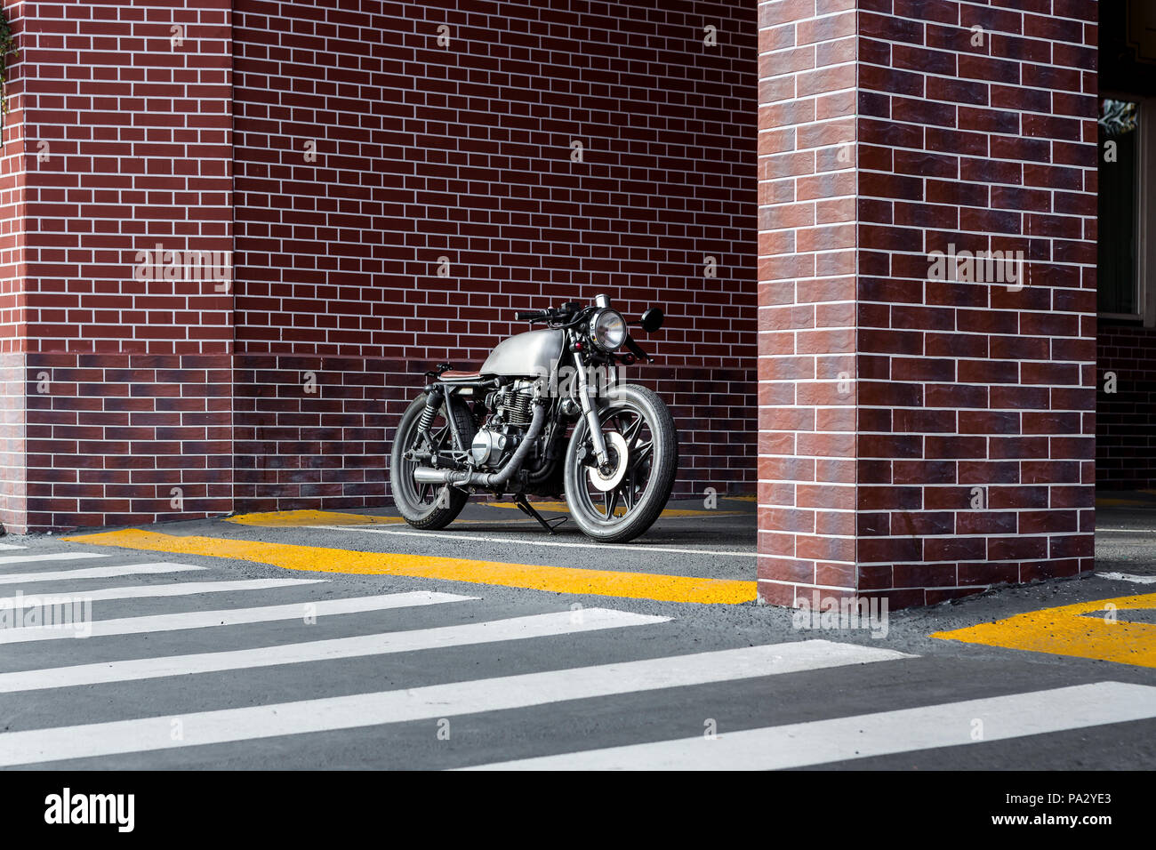 Handmade motorcyle parking near brick wall of industrial building. Everything is ready for having fun after hard day in office. Businessman city hipst Stock Photo