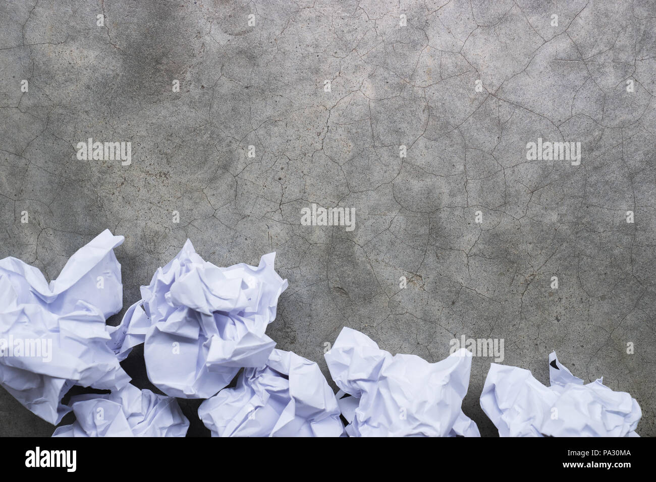 crumpled paper balls on a gray concrete surface Stock Photo