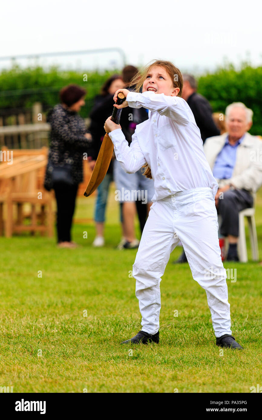 Young girl, child, 12-13 years, batting with cricket bat while dressed up in Victorian costume during cricket match. Broadstairs Dickens week festival Stock Photo