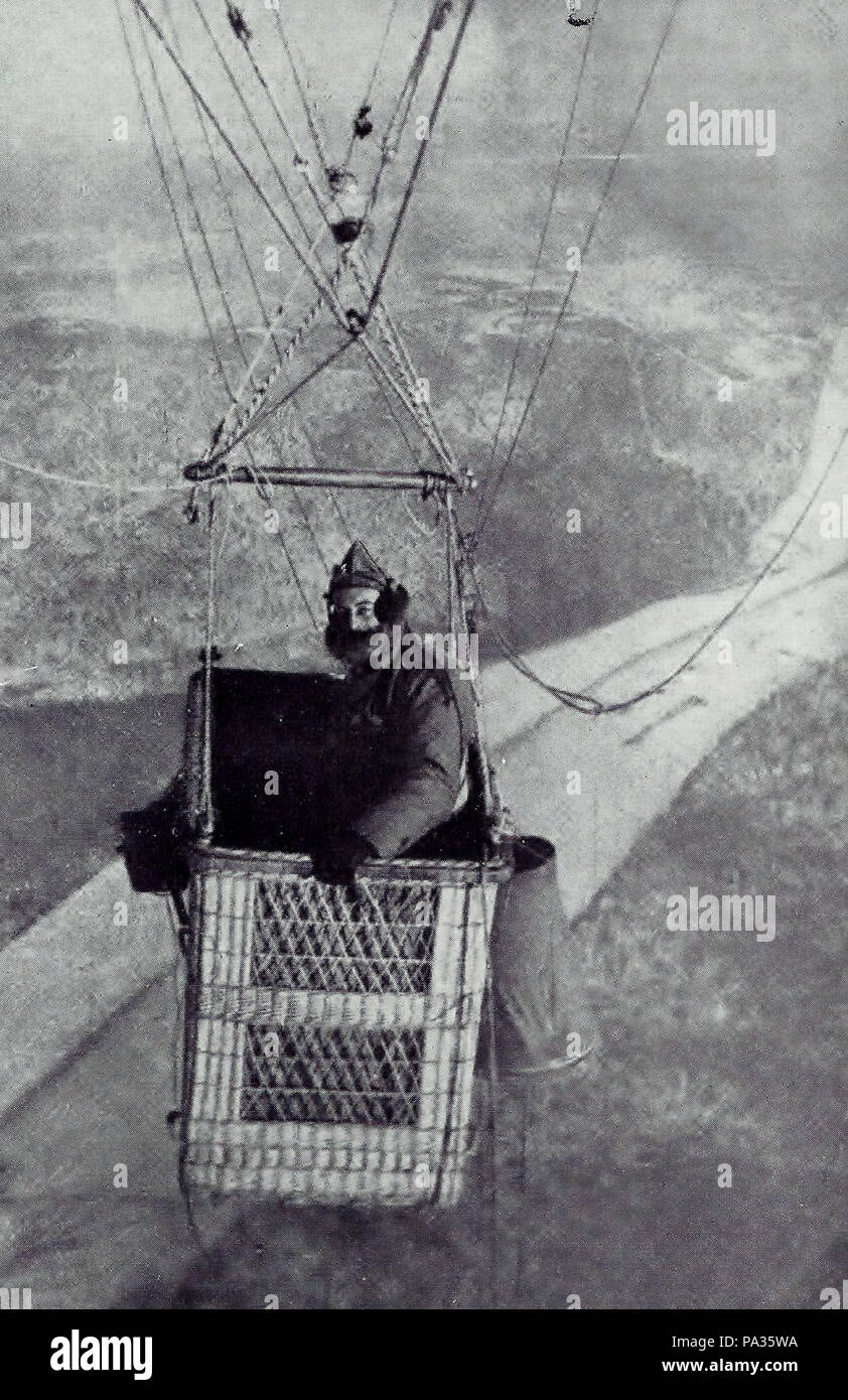 . English: French observer aboard observation balloon. Original description: FUR-MUFFLERED AND GLOVED, A FRENCH AËRONAUT PREPARED FOR A LONG STAY IN THE AIR TO OBSERVE THE ENEMY'S OPERATIONS This photograph was made from a new type of observation balloon which carries two baskets. The second basket, accommodating the photographer, hangs very near the one shown in the picture. between 1914 and 1918 102 Aerial observer in balloon gondola, 1918 Stock Photo