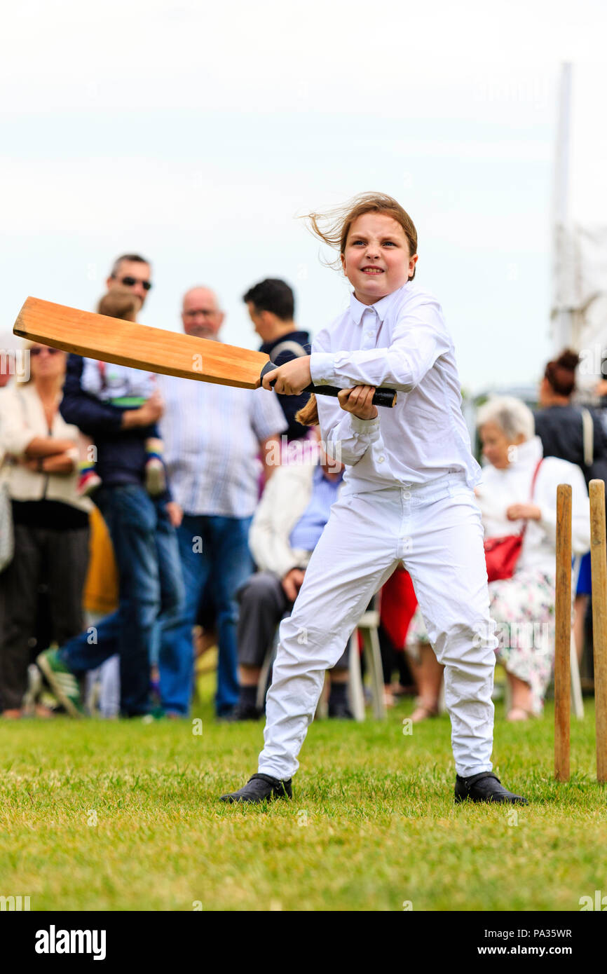 Young girl, child, 12-13 years, batting with cricket bat while dressed up in Victorian costume during cricket match. Broadstairs Dickens week festival Stock Photo