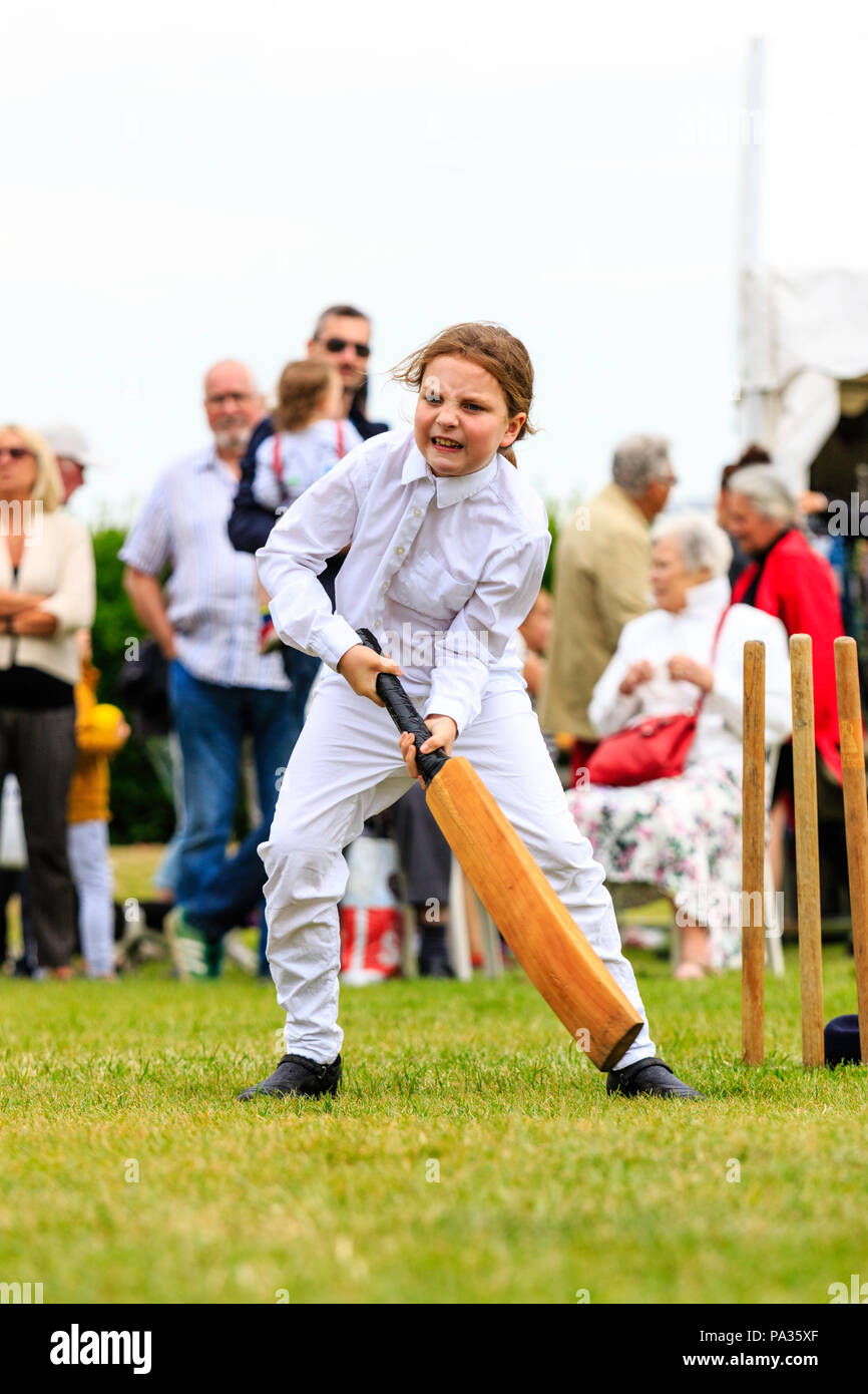 Young girl, child, 12-13 years, batting with cricket bat while dressed up in Victorian costume during cricket match. Broadstairs Dickens week festival Stock Photo